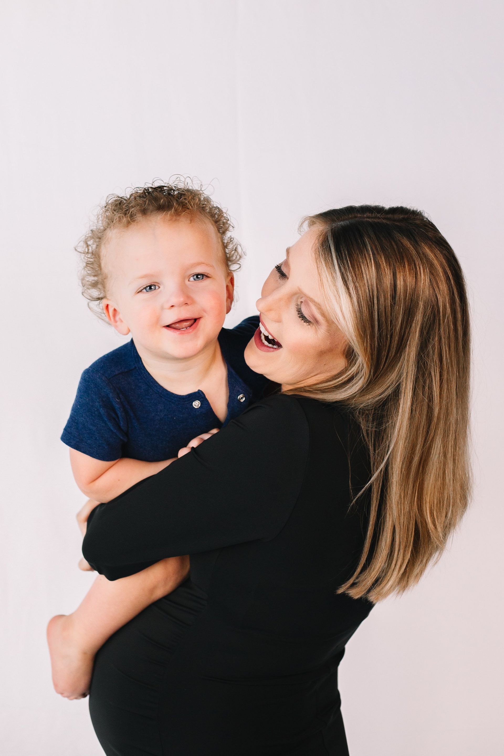 A pregnant woman is holding a little boy in her arms.