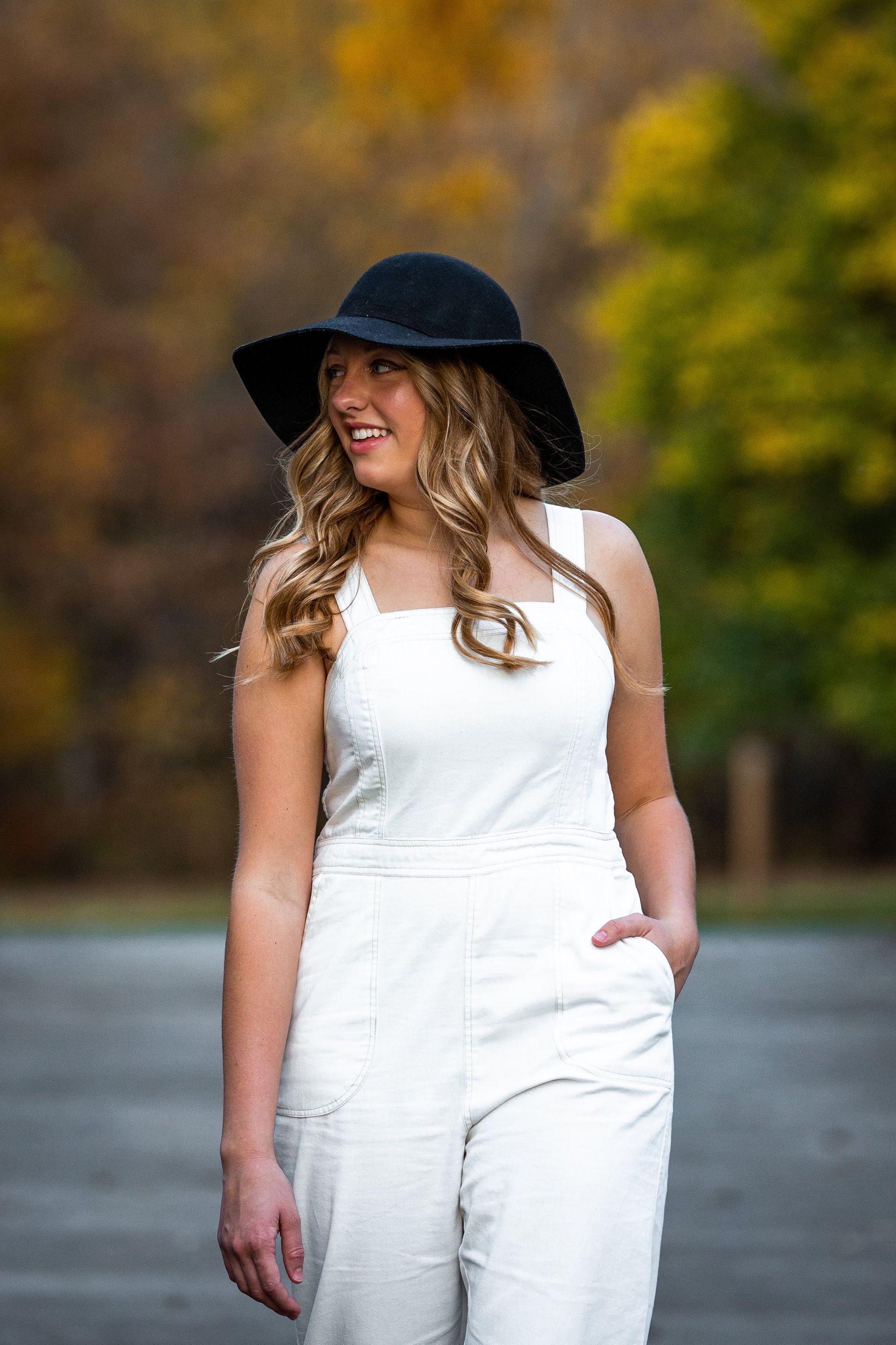 The woman is wearing a white jumpsuit and a black hat.