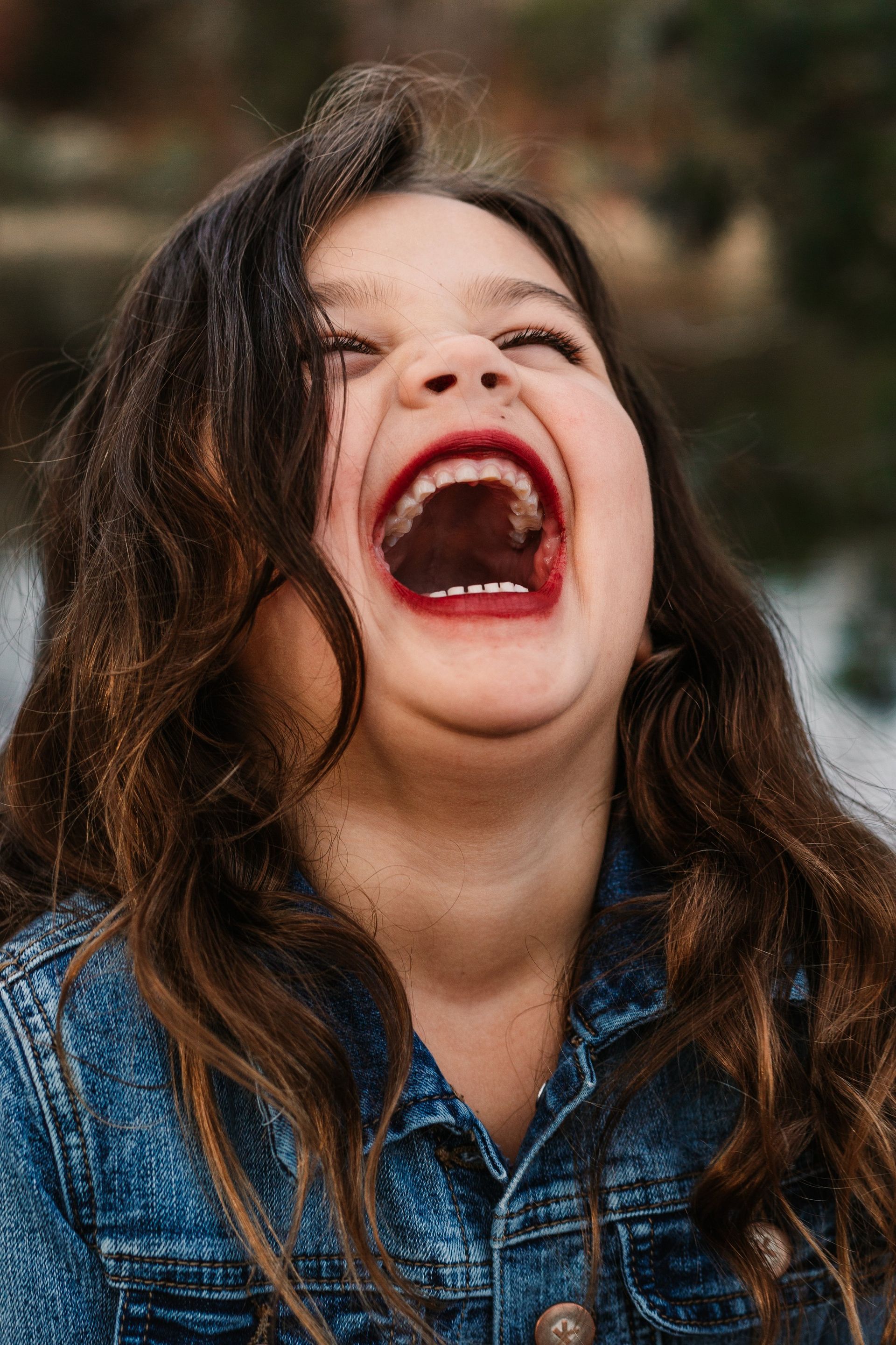 A young girl is laughing with her mouth open.