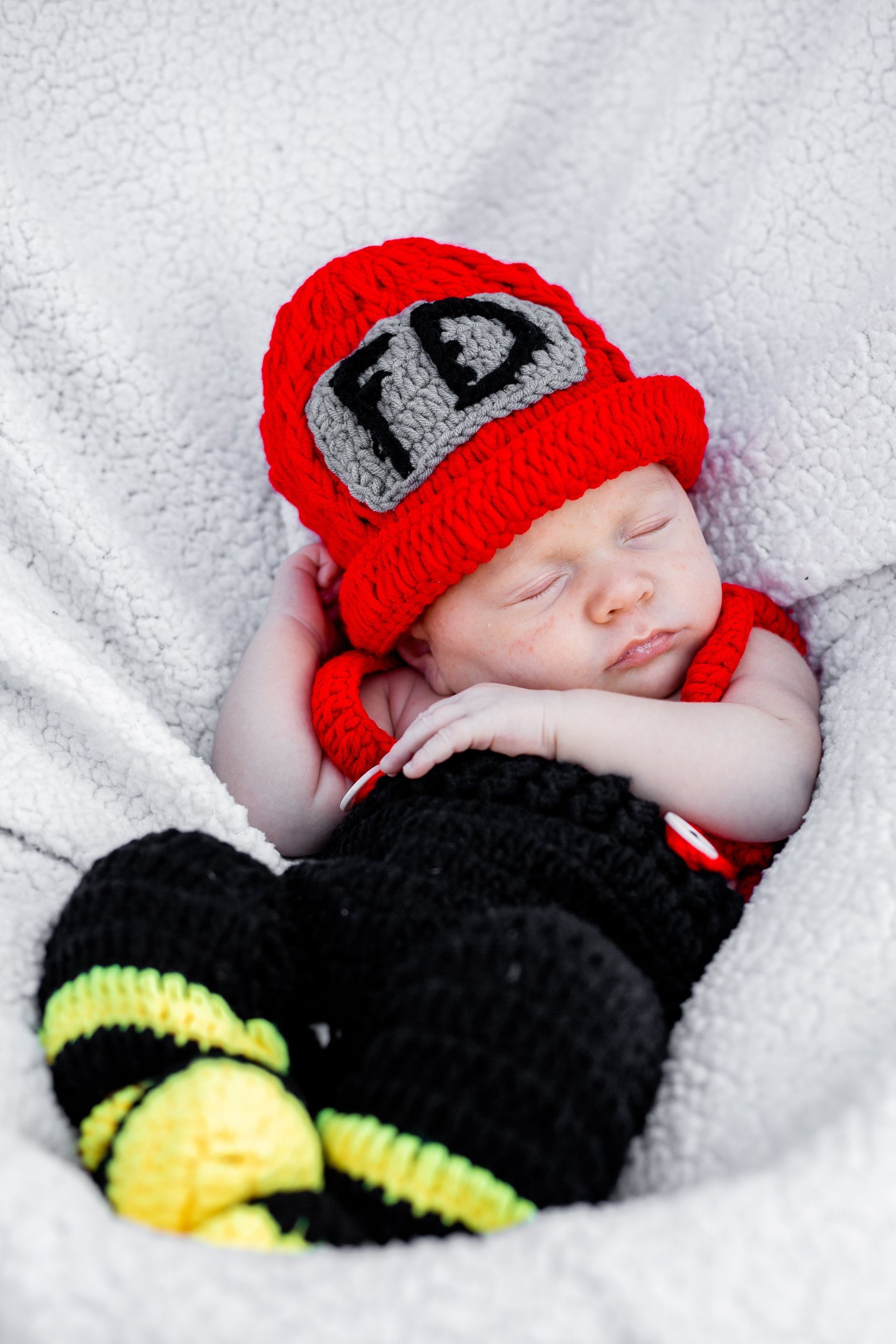 A baby wearing a red hat with the letter fd on it