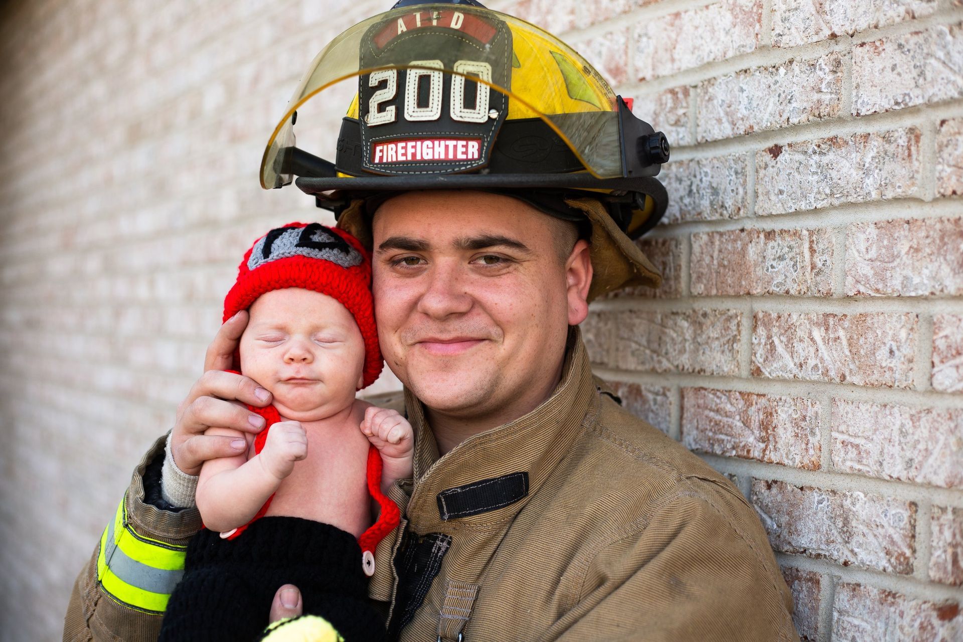 A fireman is holding a baby in his arms.