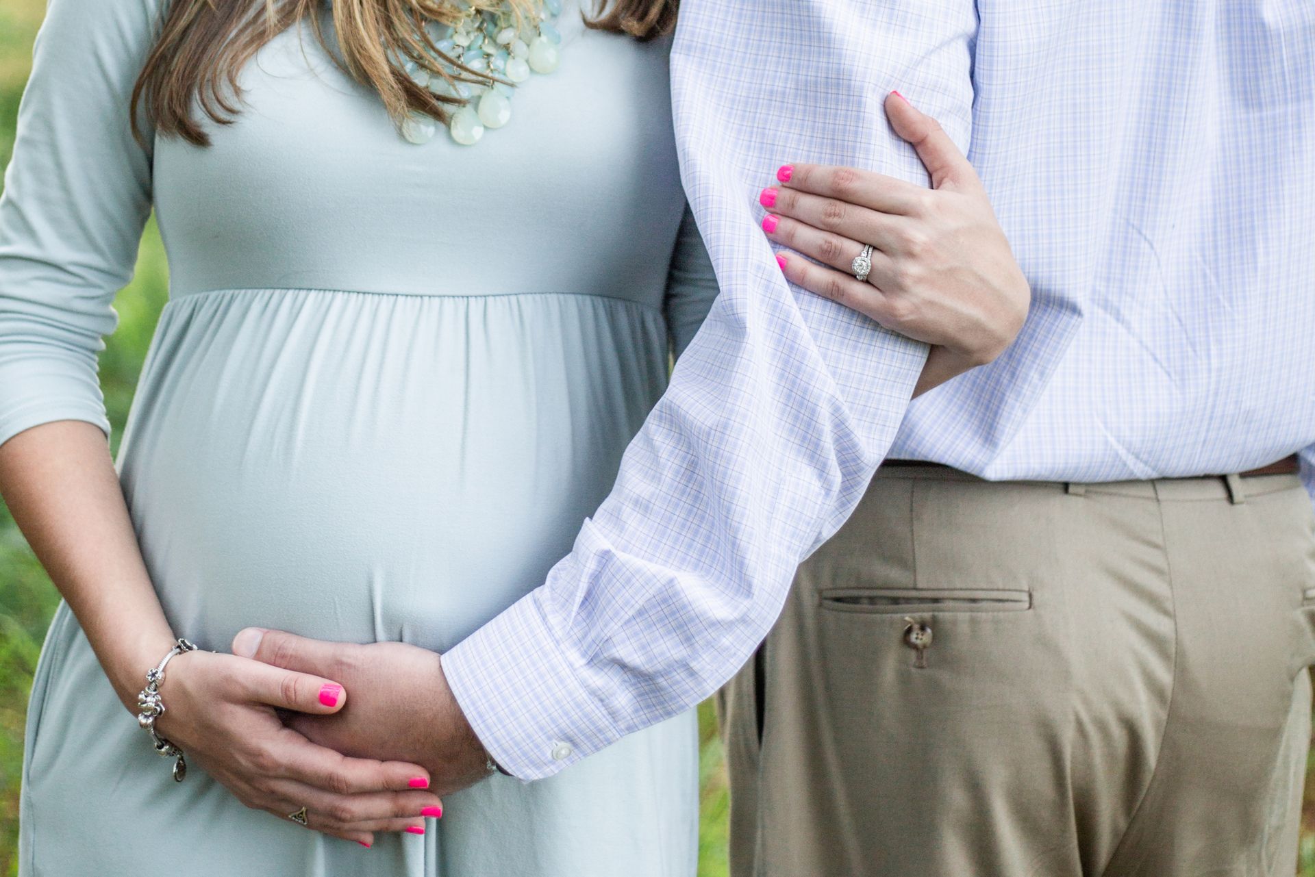 A pregnant woman and her husband touch her tummy.