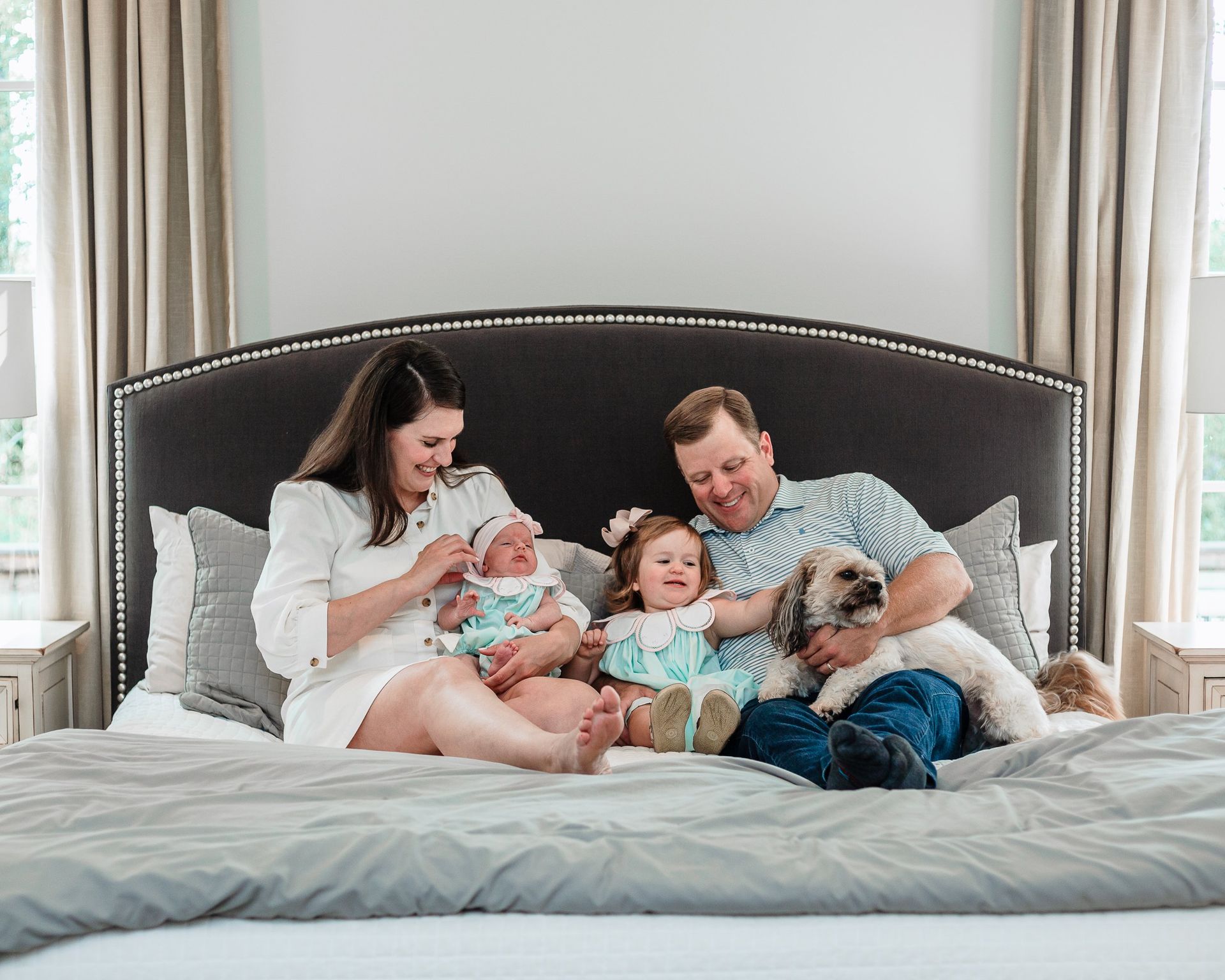 A family is sitting on a bed with a dog.