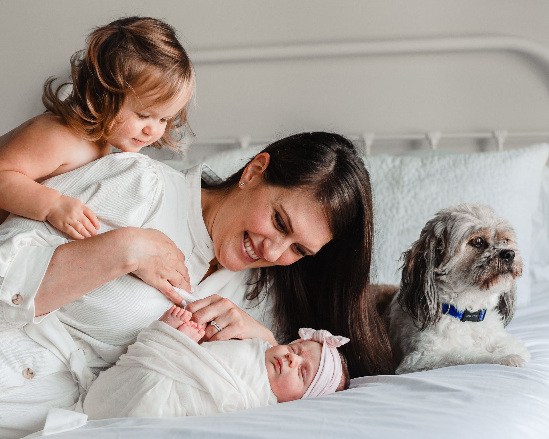 A woman is laying on a bed with two children and a dog.