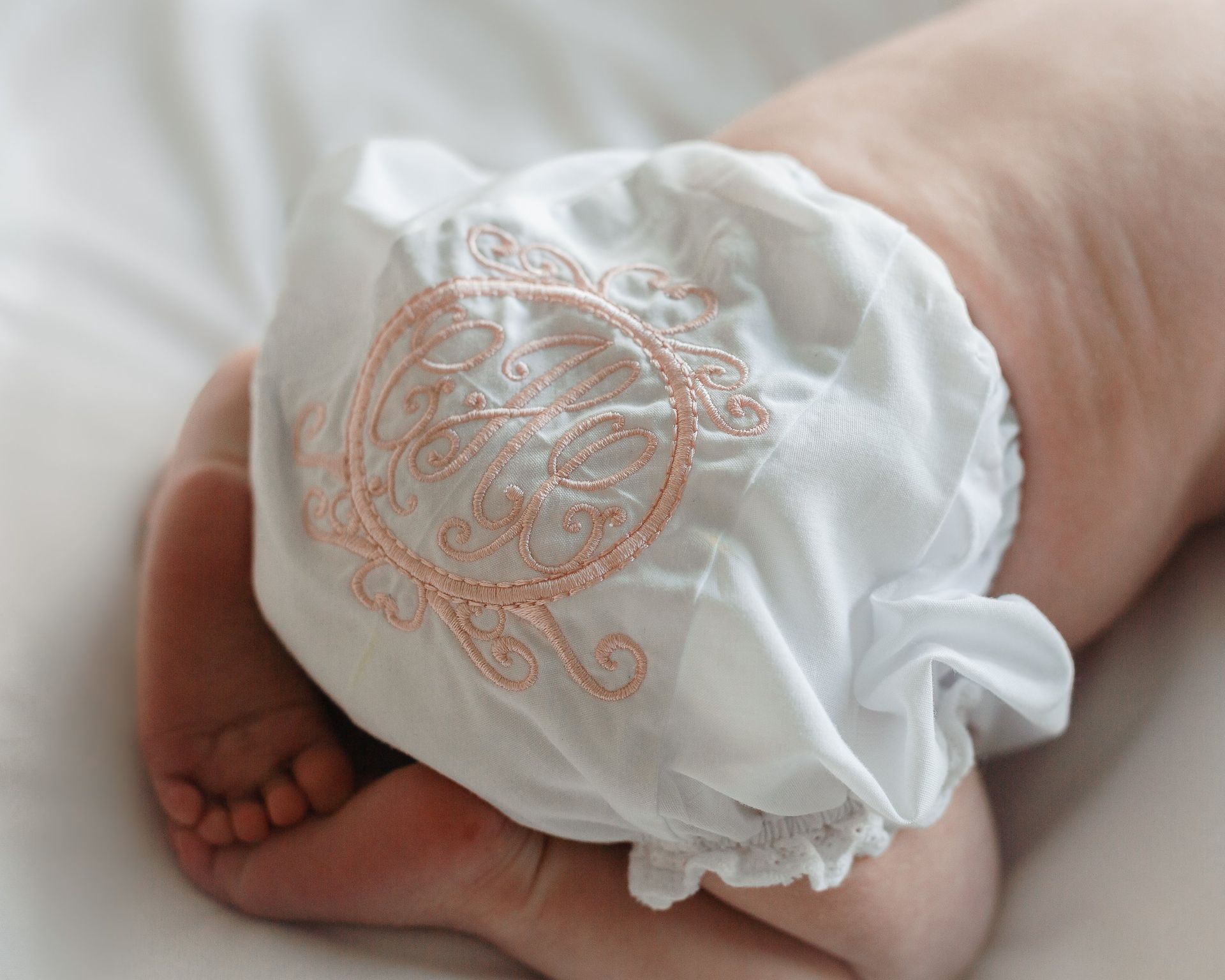 A baby wearing a white diaper with a monogram on it