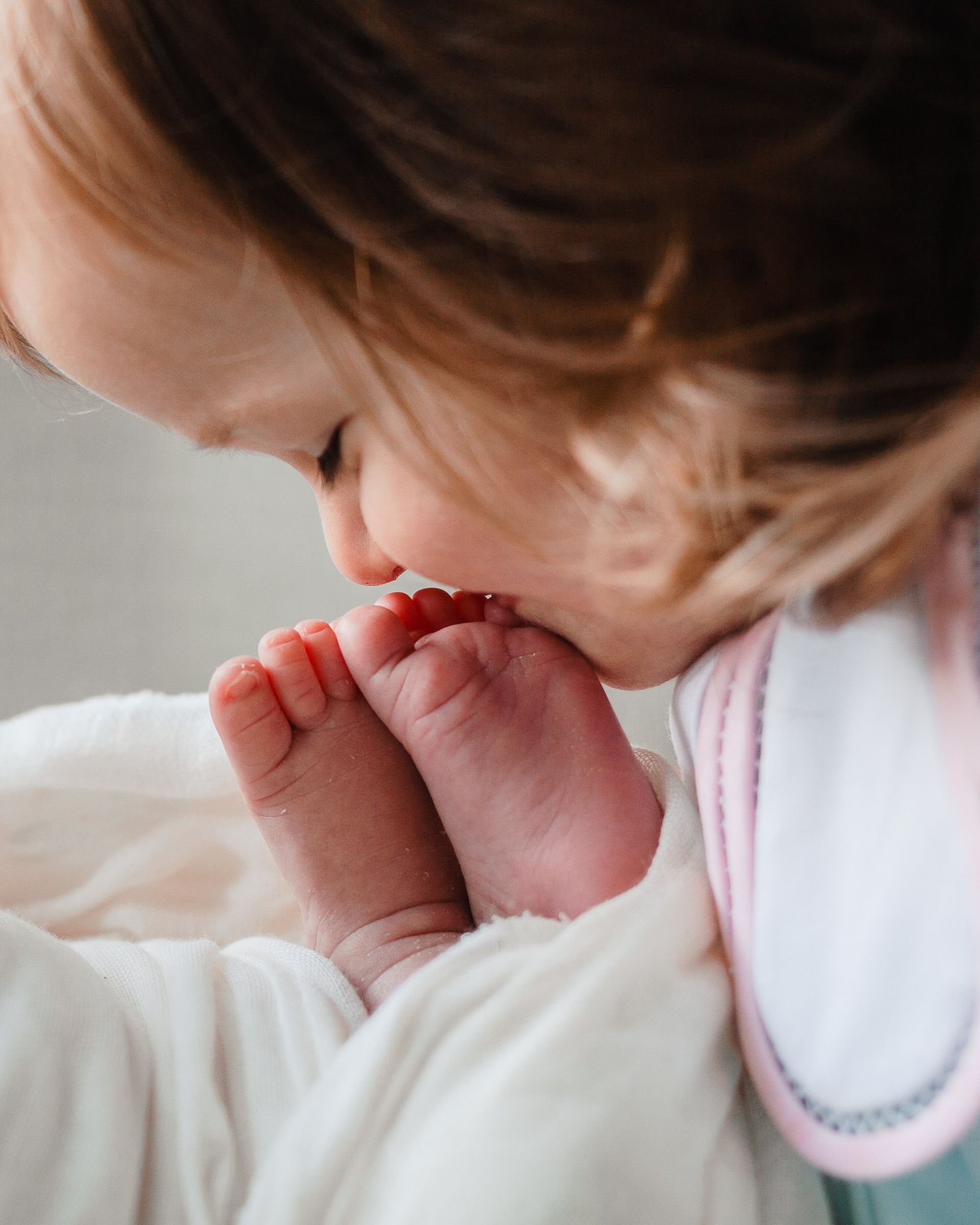 Young girl looking at a baby's feet.