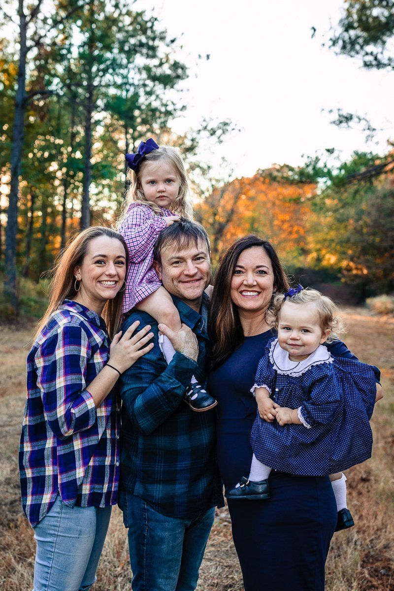 A family is posing for a picture in the woods.