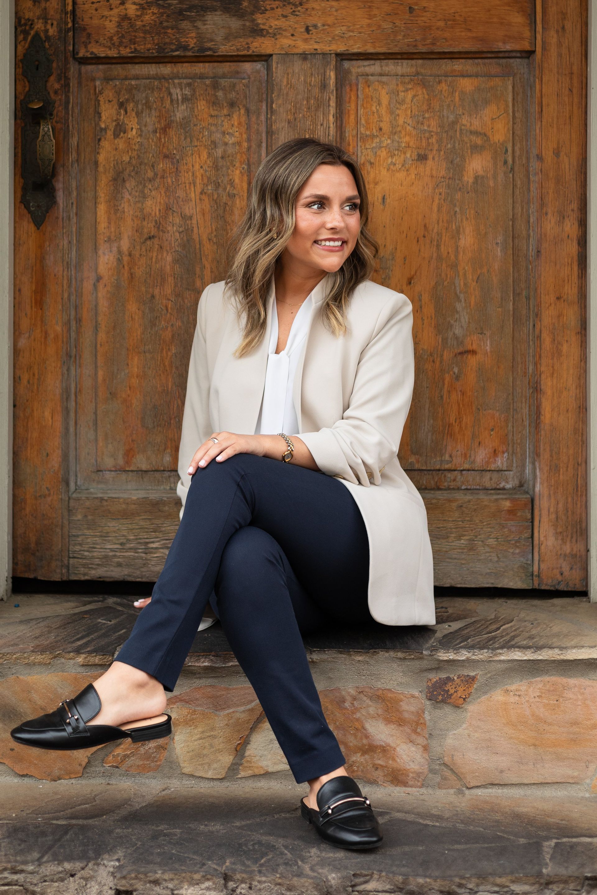 A woman is sitting on the steps of a door.