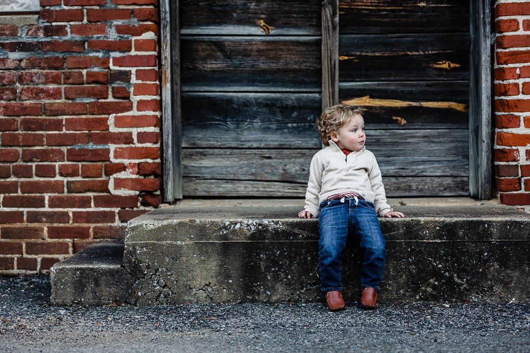 A little girl is sitting on the steps of a brick building.