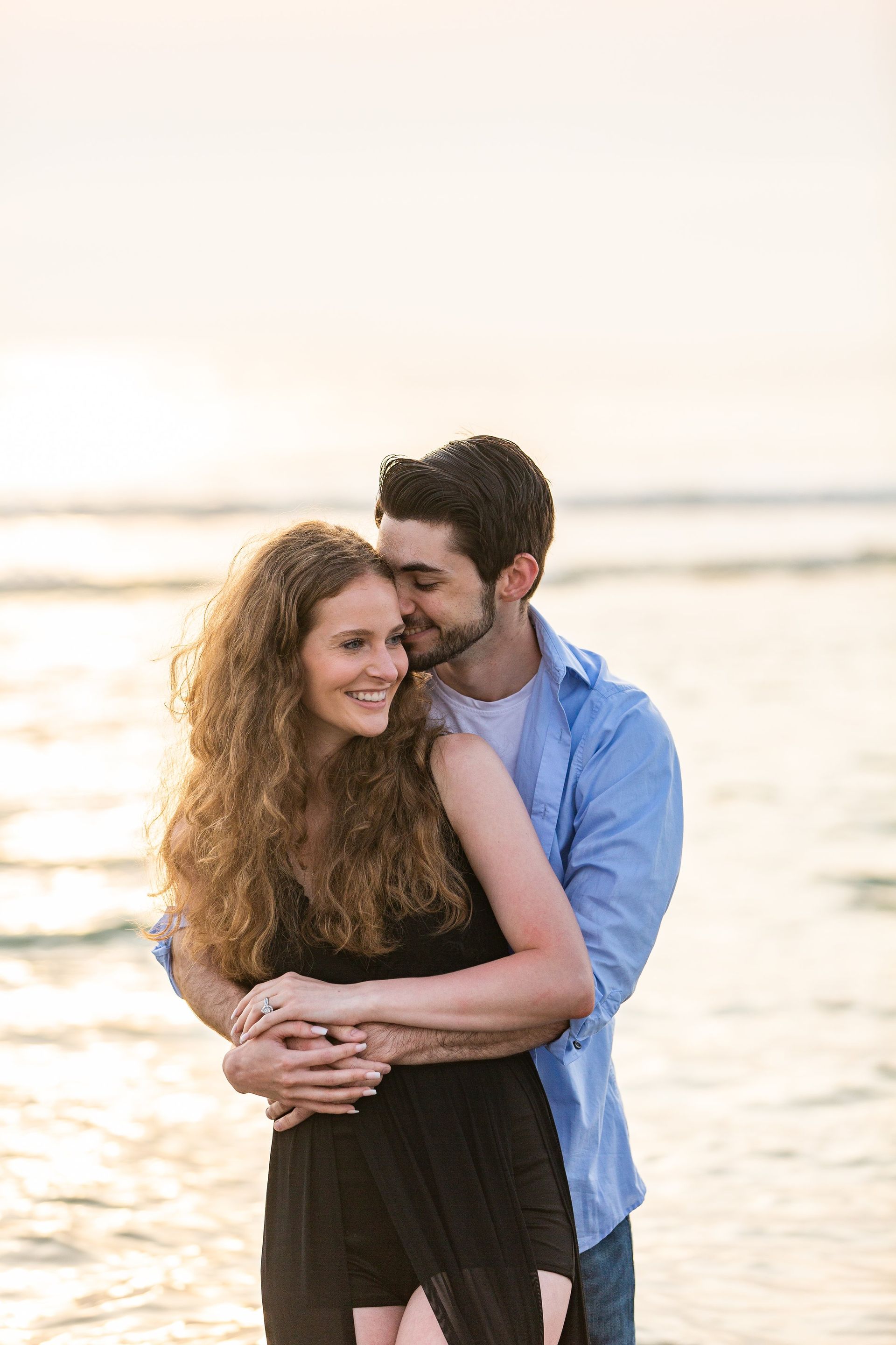 A man and a woman are hugging each other on the beach.