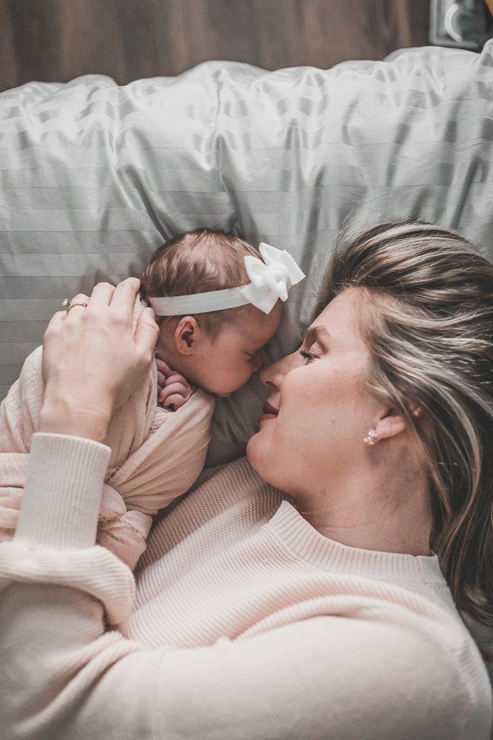 A woman is laying on a couch holding a newborn baby.