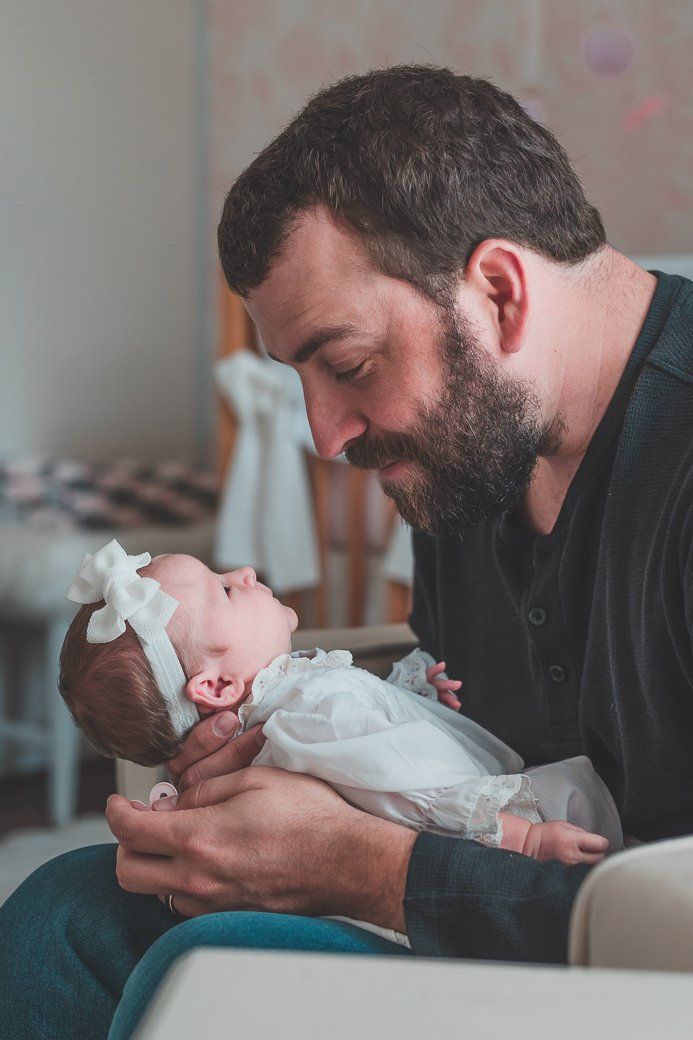 A man is holding a baby in his arms while sitting on a couch.