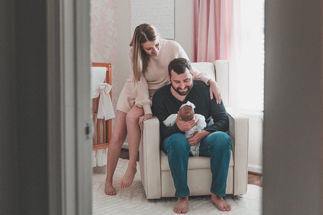 A man and a woman are sitting in a chair holding a baby.
