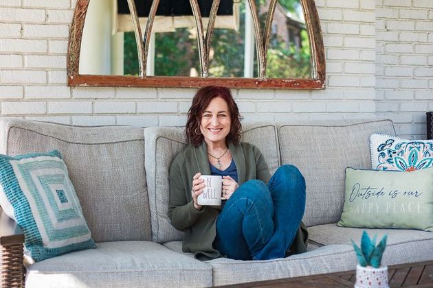 A woman is sitting on a couch holding a cup of coffee.