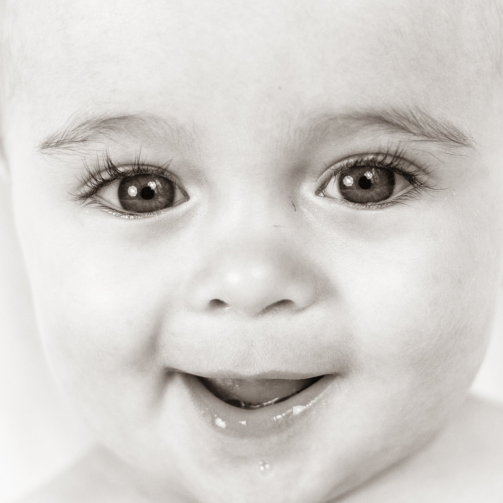 A baby is smiling in a black and white photo