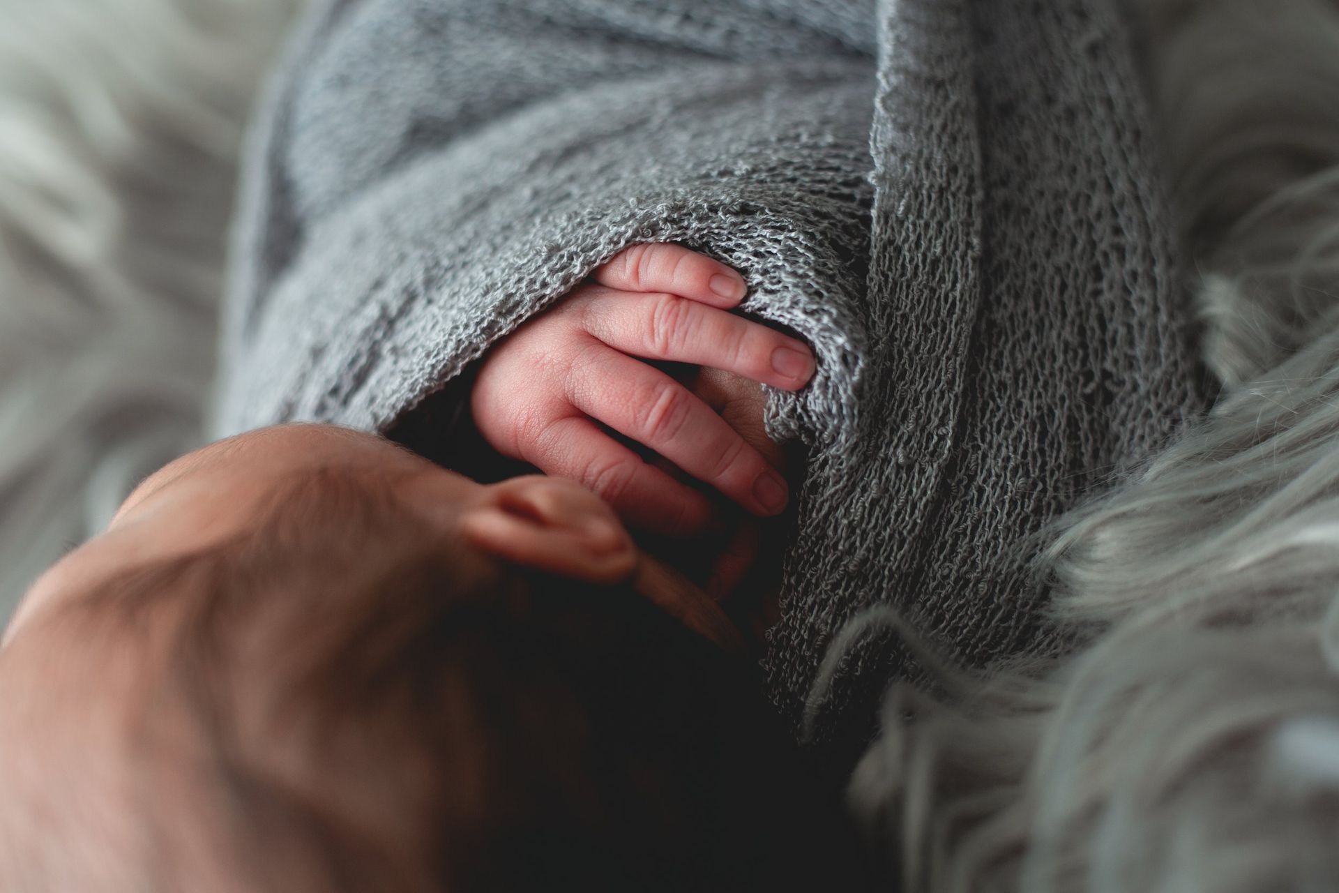 A close up of a baby 's hand wrapped in a blanket.