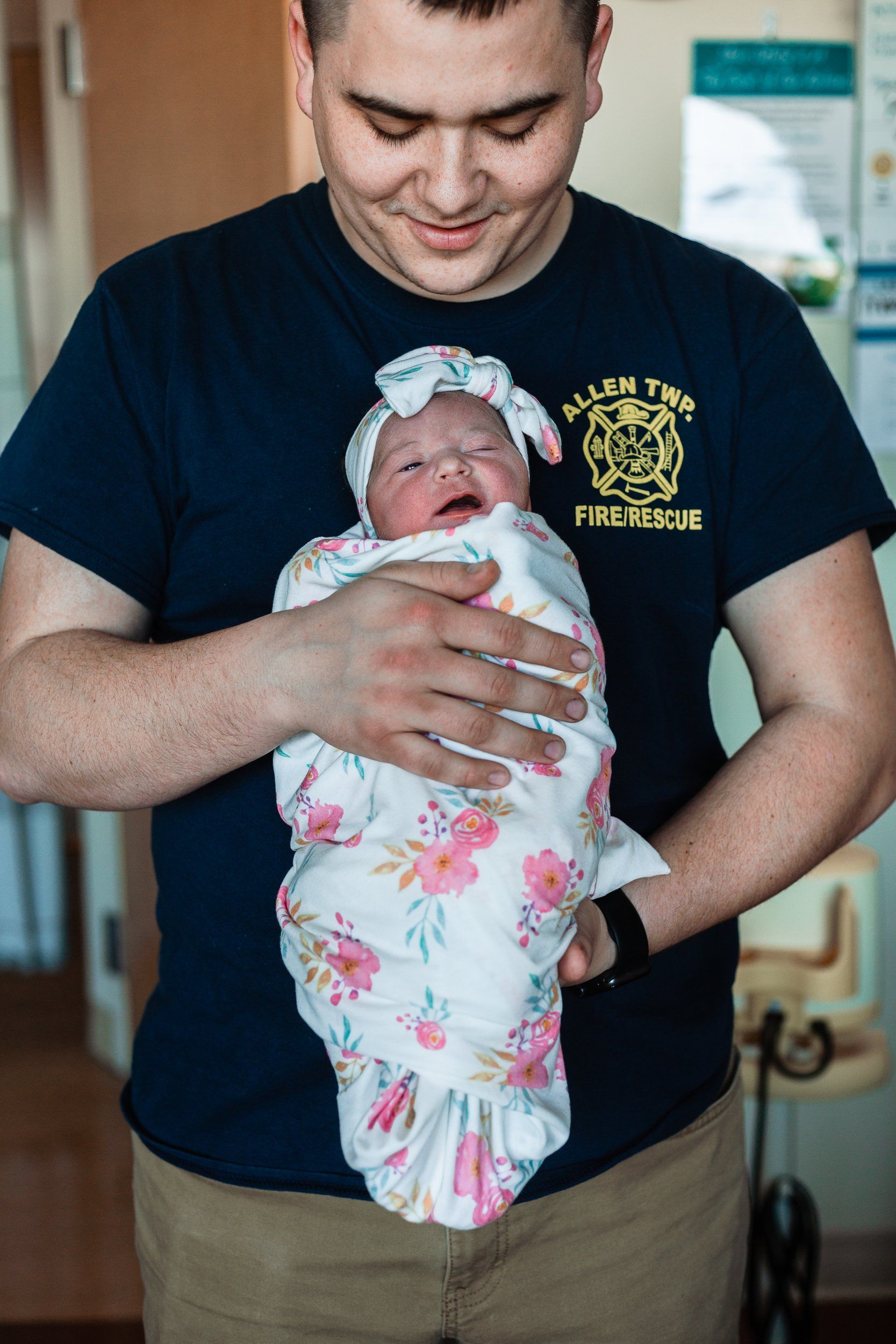 A man is holding a newborn baby wrapped in a blanket.