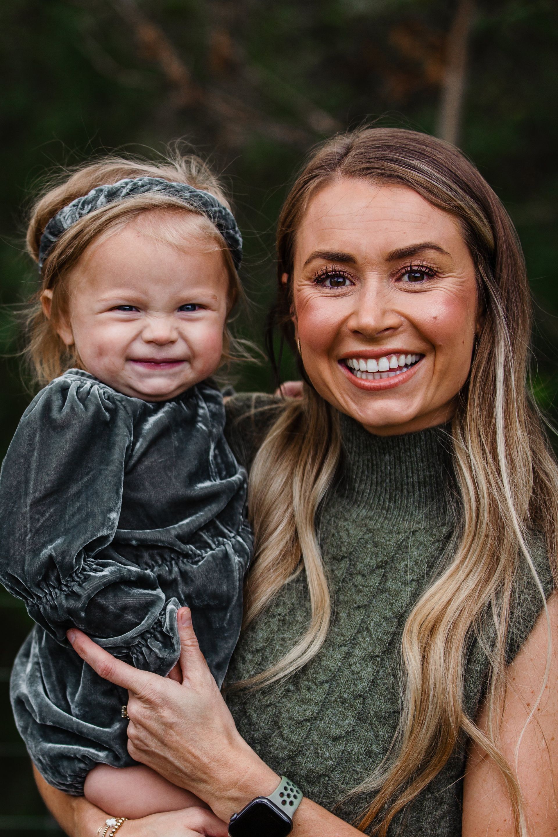 A woman is holding a little girl in her arms and smiling.