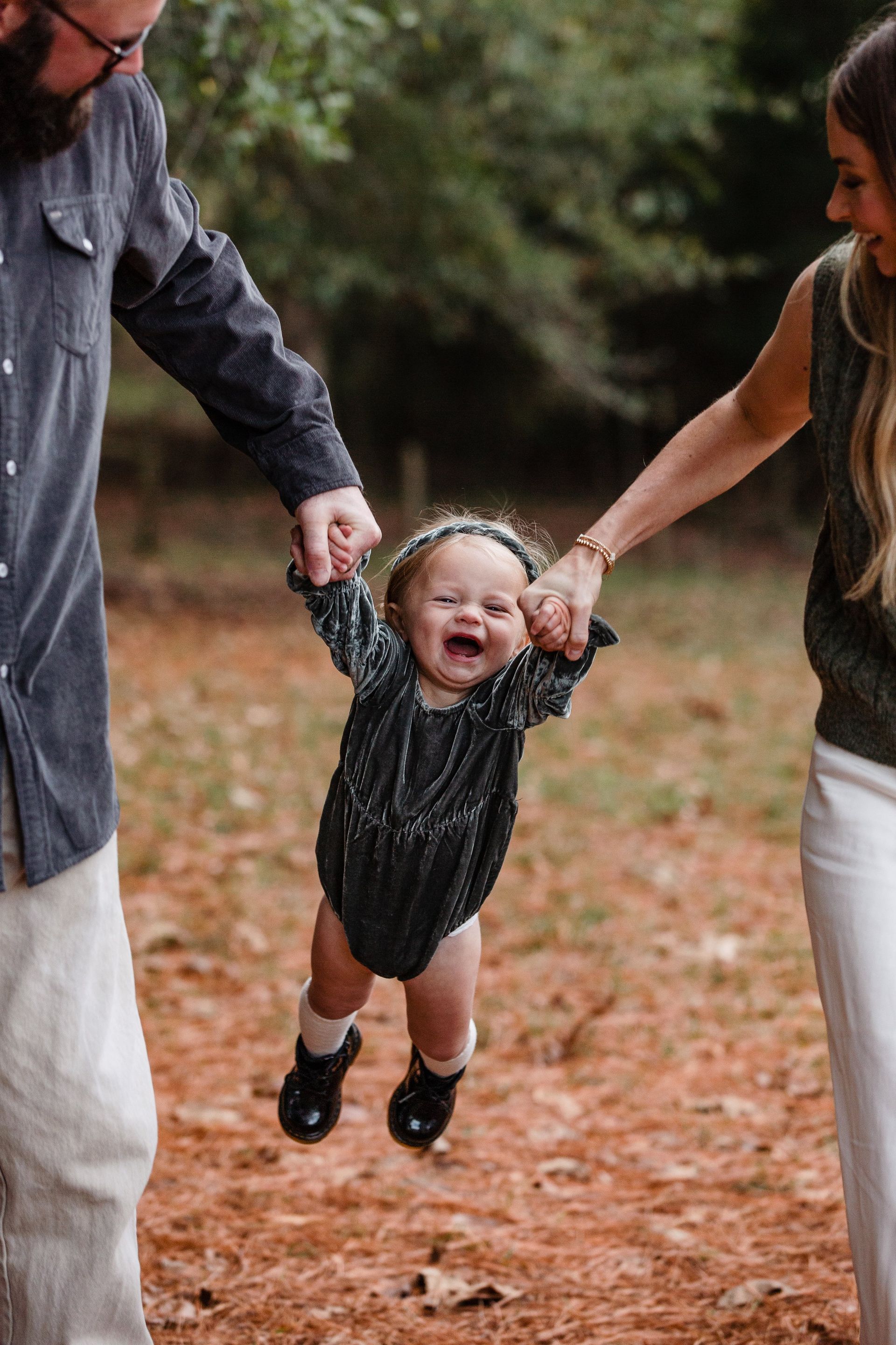 A man and woman are holding a baby in the air.