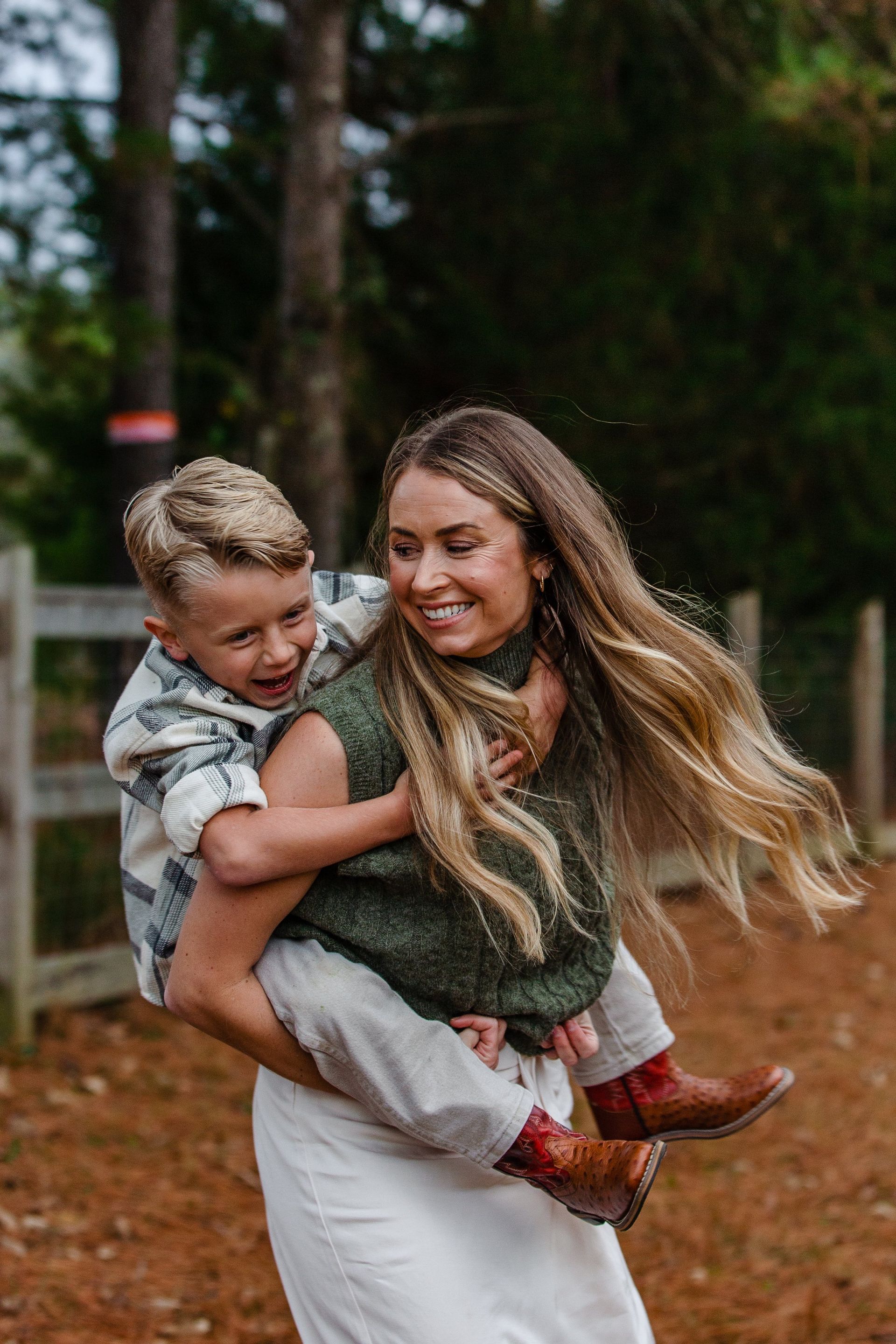 A woman is carrying a little boy on her back.