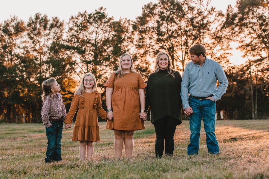 A family is standing in a field holding hands.