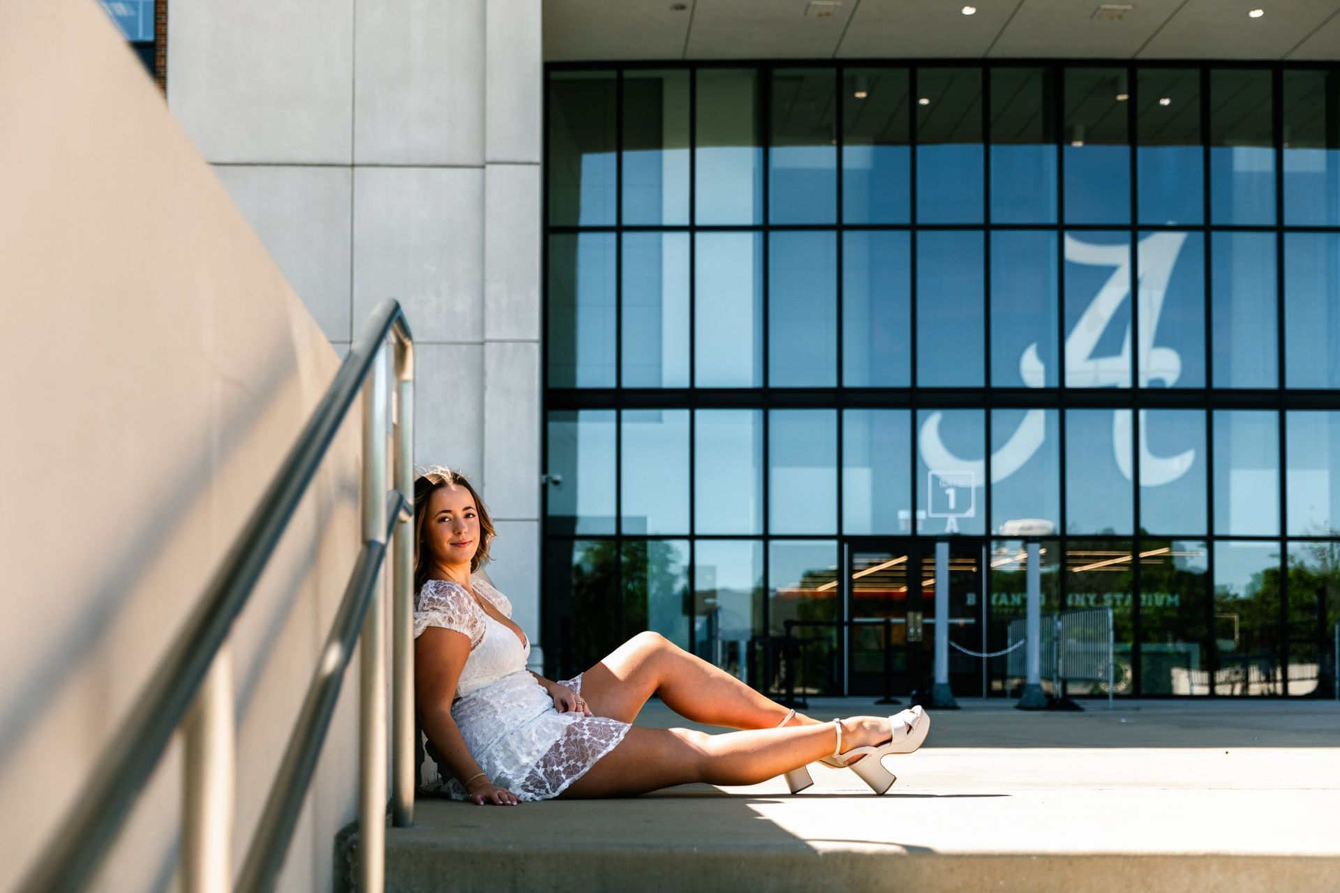 A woman in a white dress is sitting on the steps of a building.
