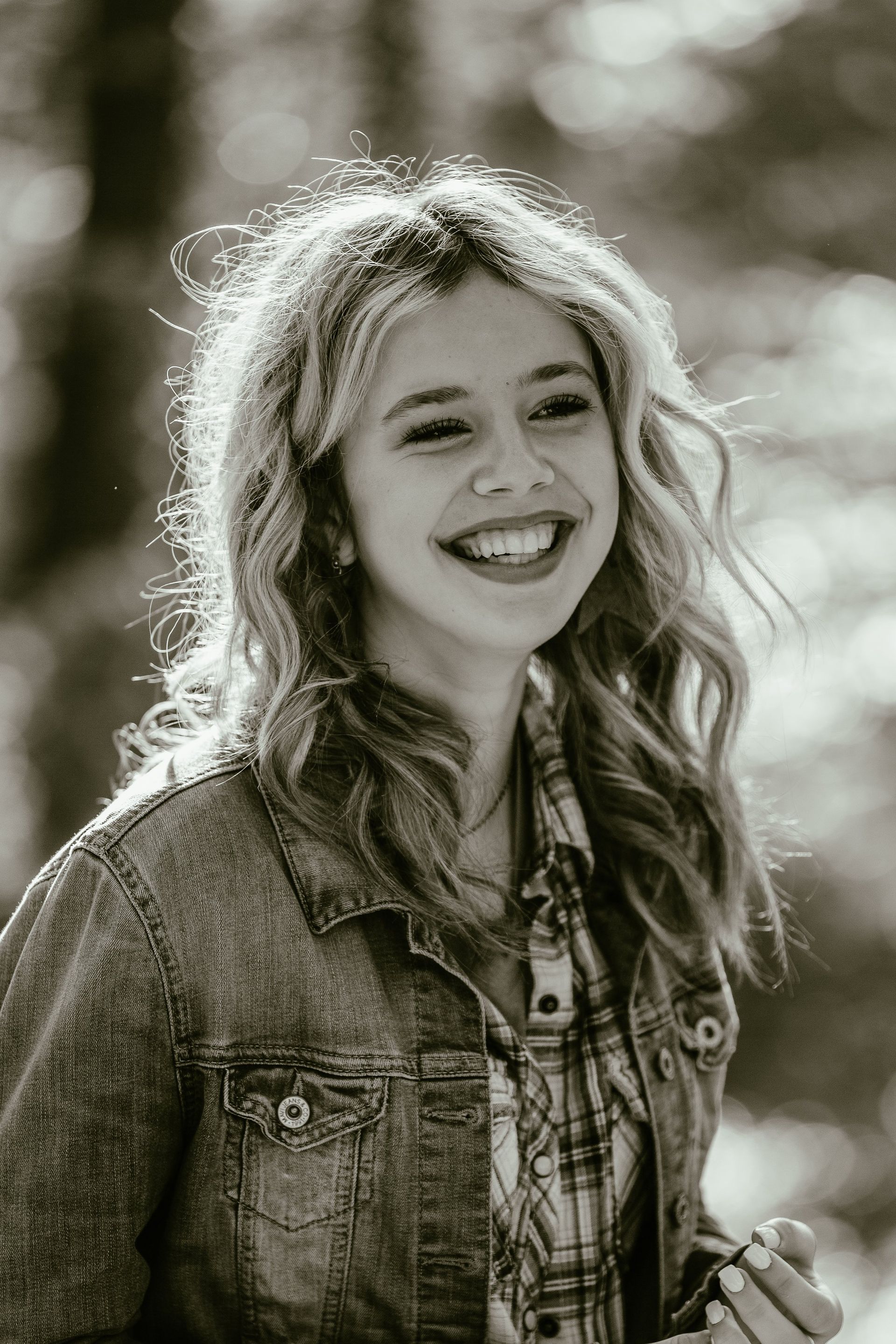 A black and white photo of a young woman wearing a denim jacket and smiling.