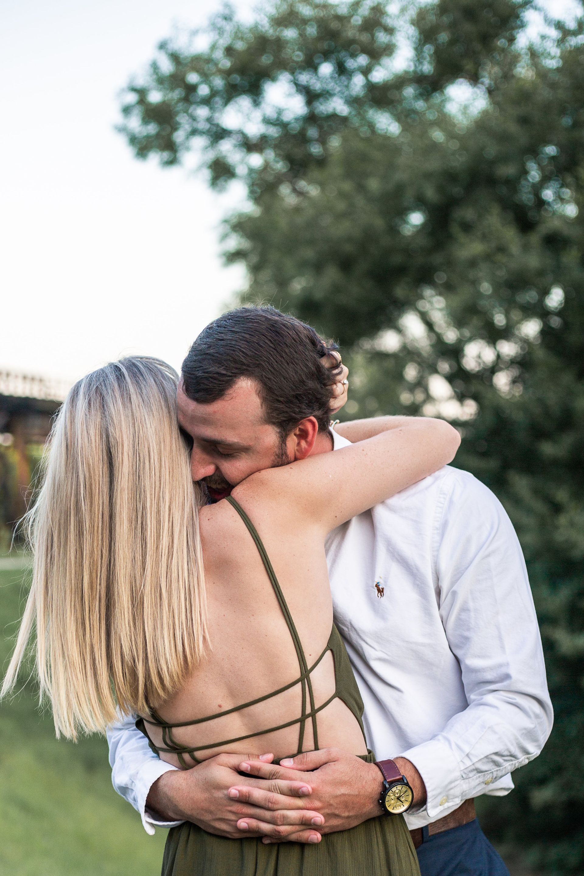 A man is kissing a woman on the back of her head.