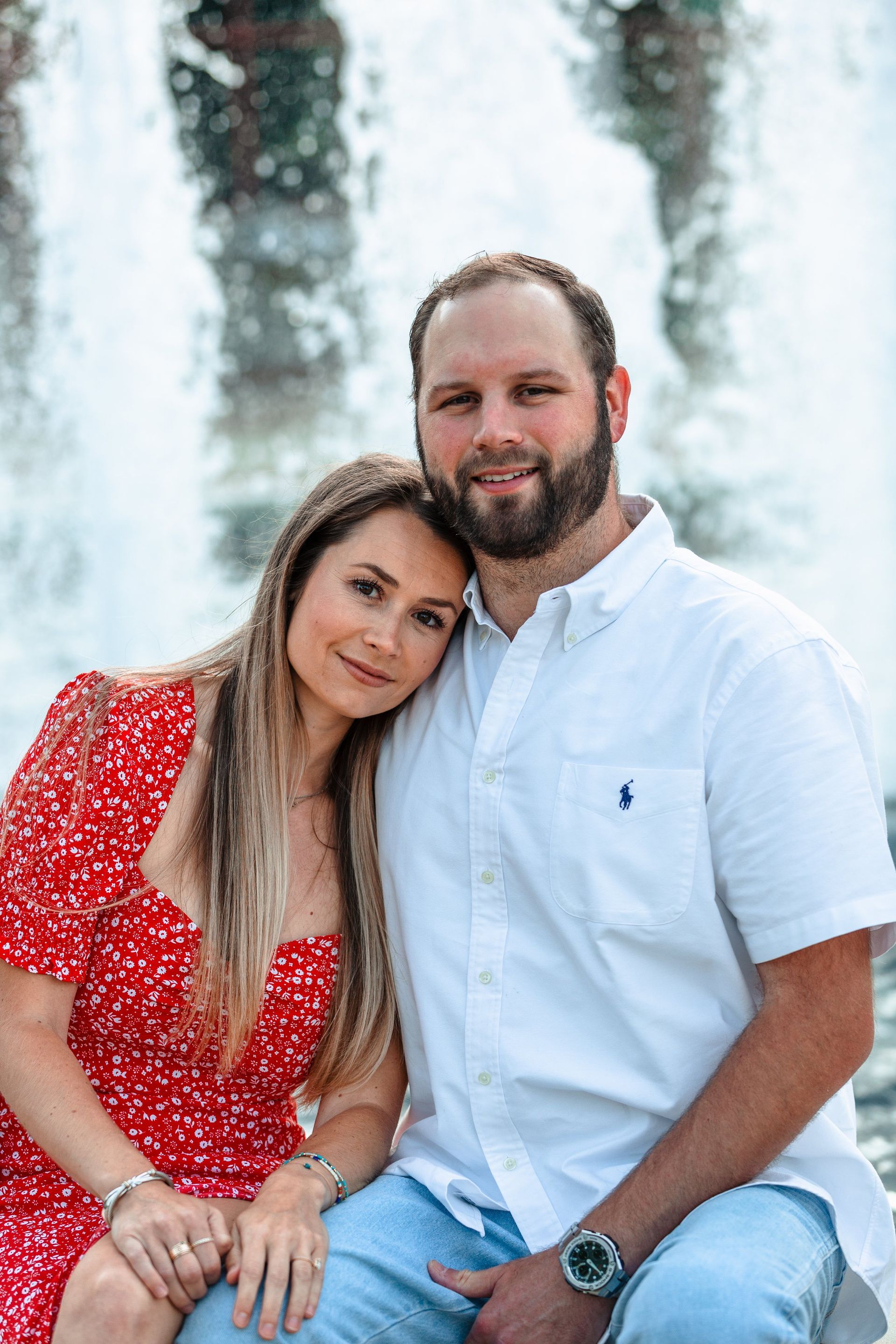 A man and a woman are sitting next to each other in front of a waterfall.