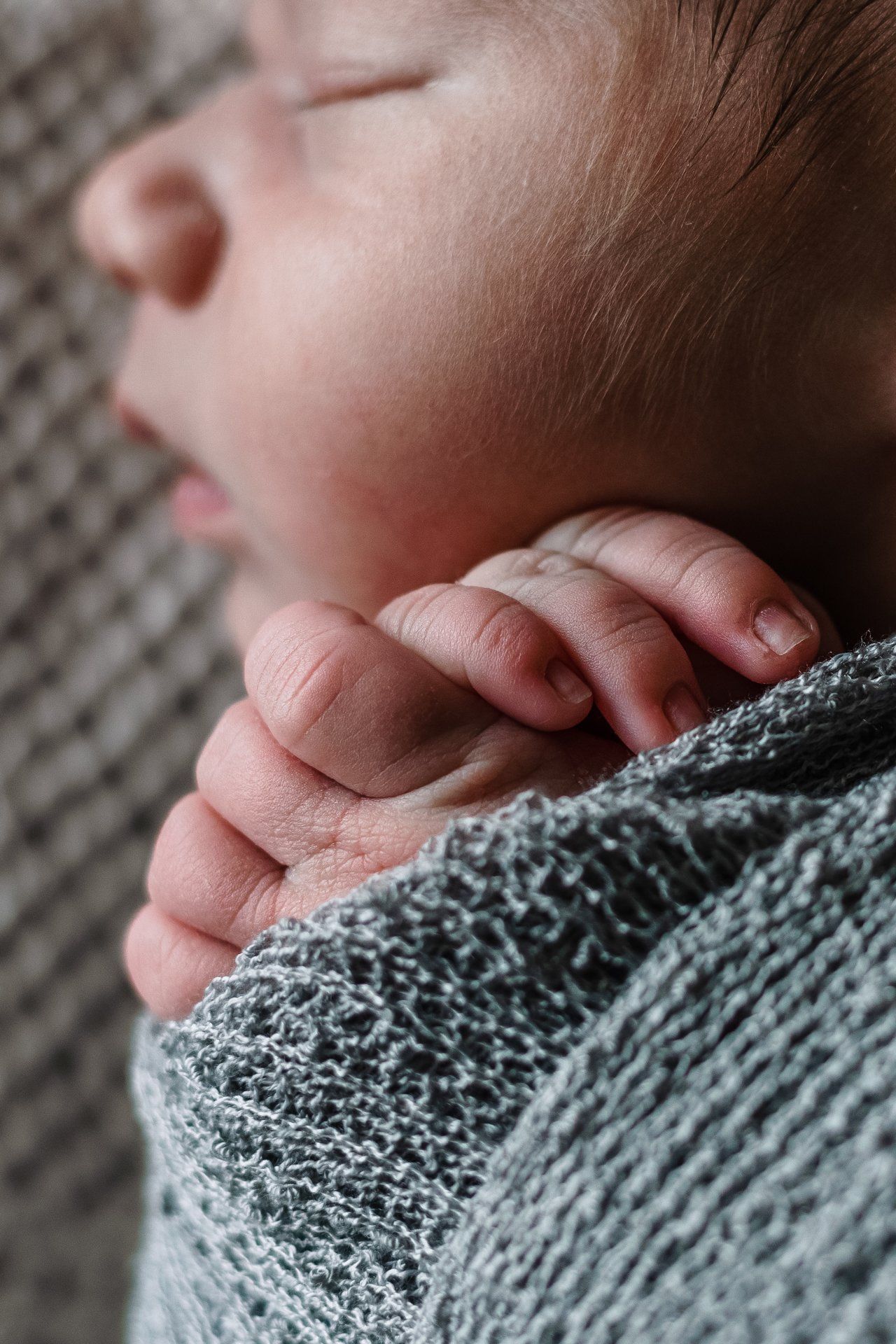 A close up of a baby 's hand wrapped in a blanket.