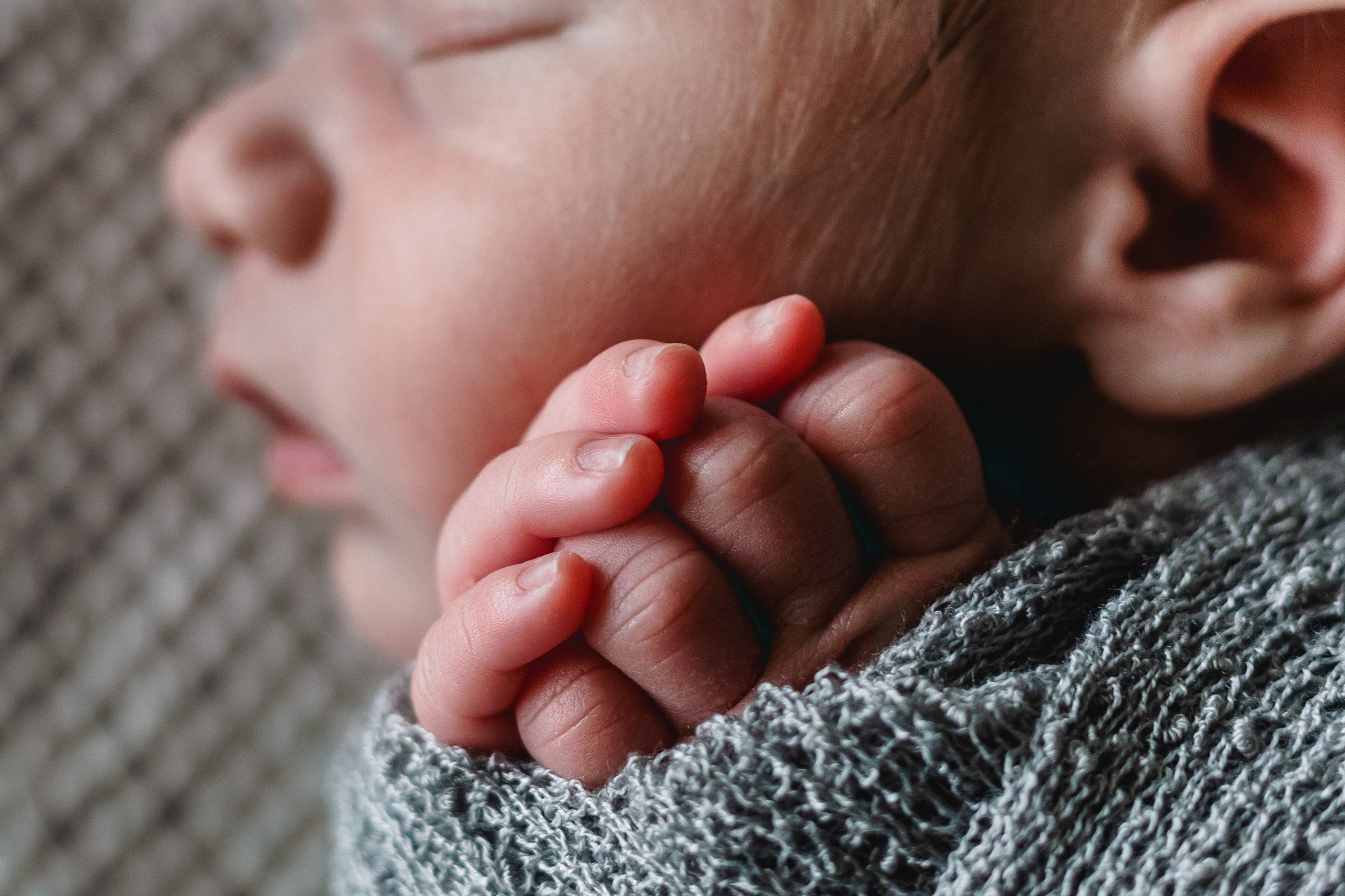 A close up of a baby 's hand wrapped in a blanket.
