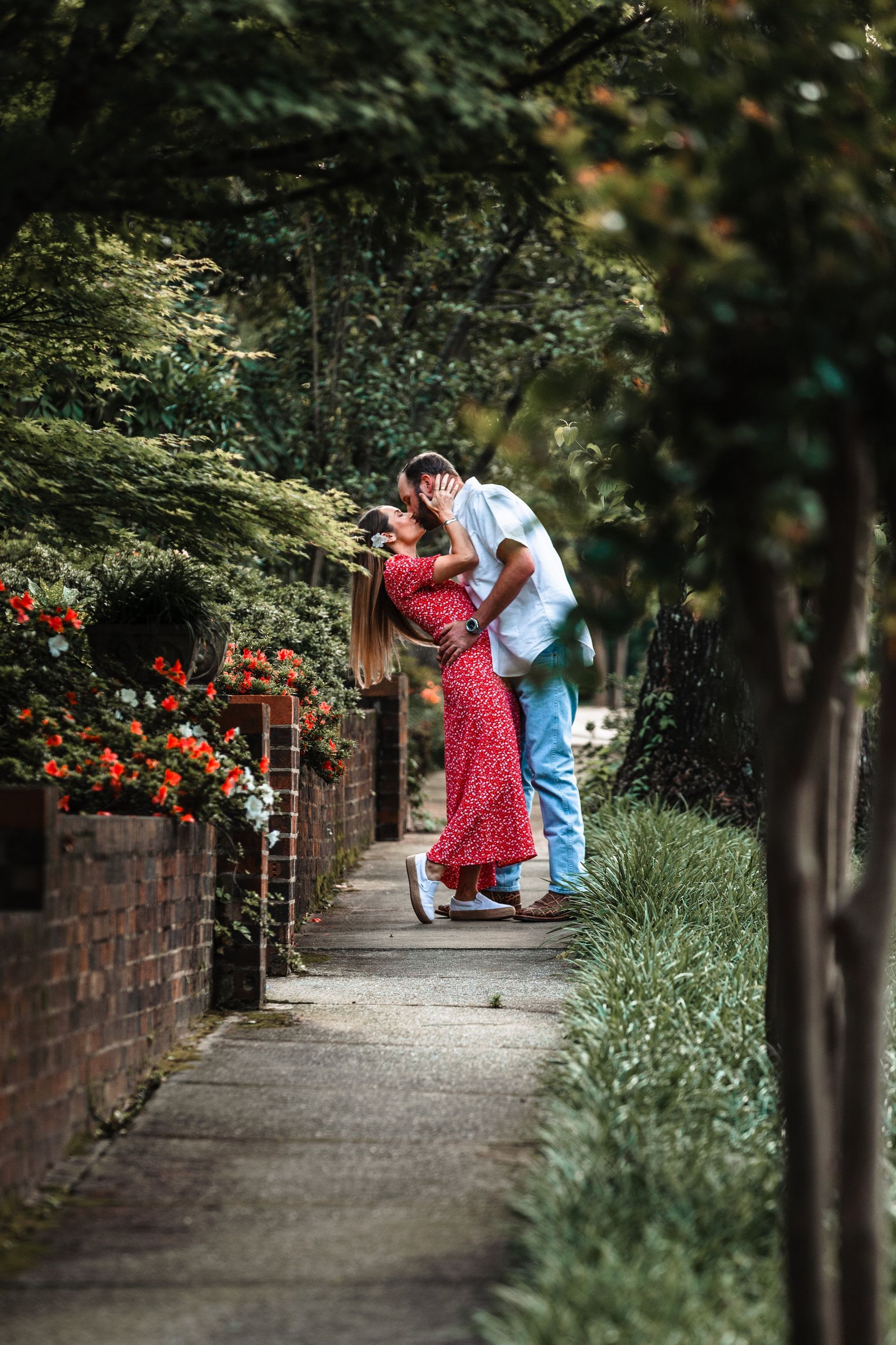 A man and a woman are kissing on a sidewalk.