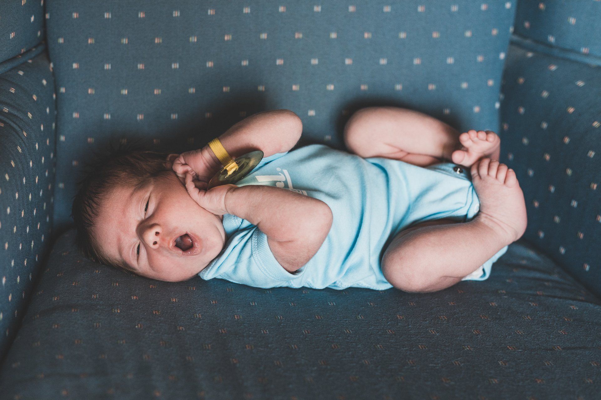 A baby is laying on a couch with a bottle in his mouth.