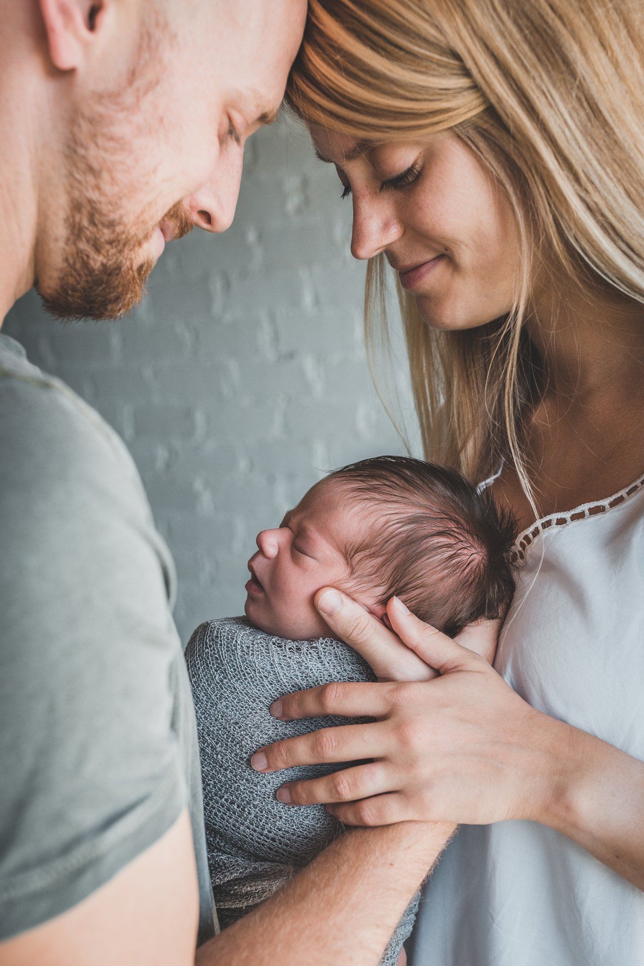 A man and a woman are holding a newborn baby.