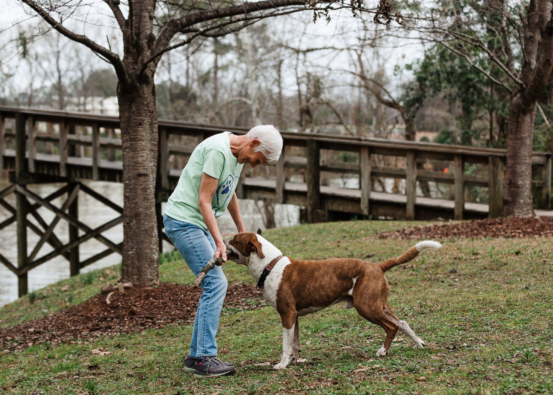 A man is playing with a dog in a park.