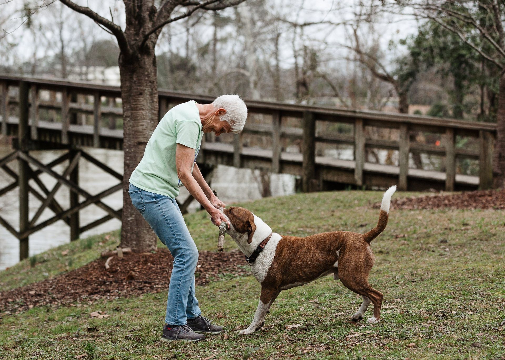 A man is playing with a dog in a park.