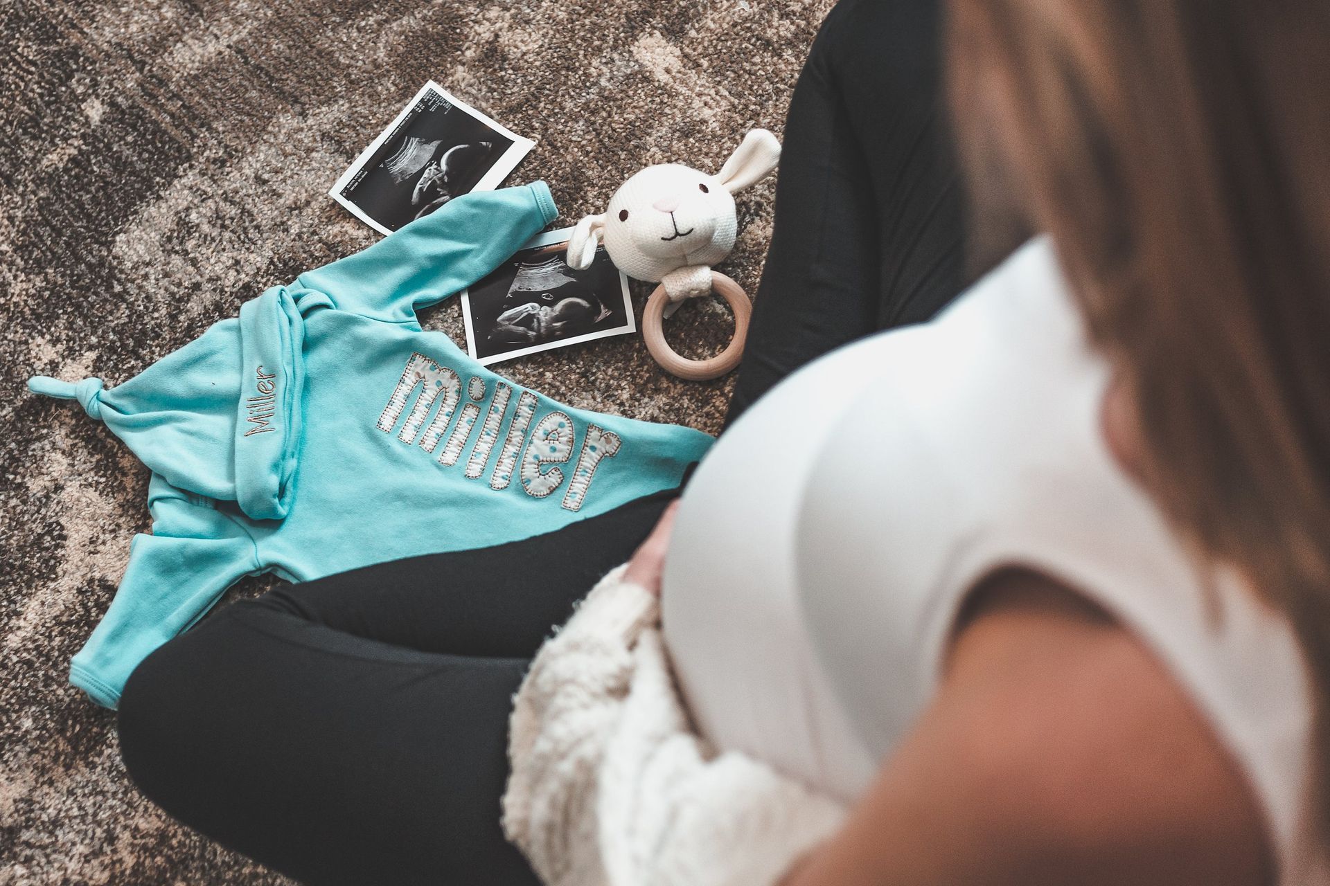 A pregnant woman is sitting on the floor holding her belly.
