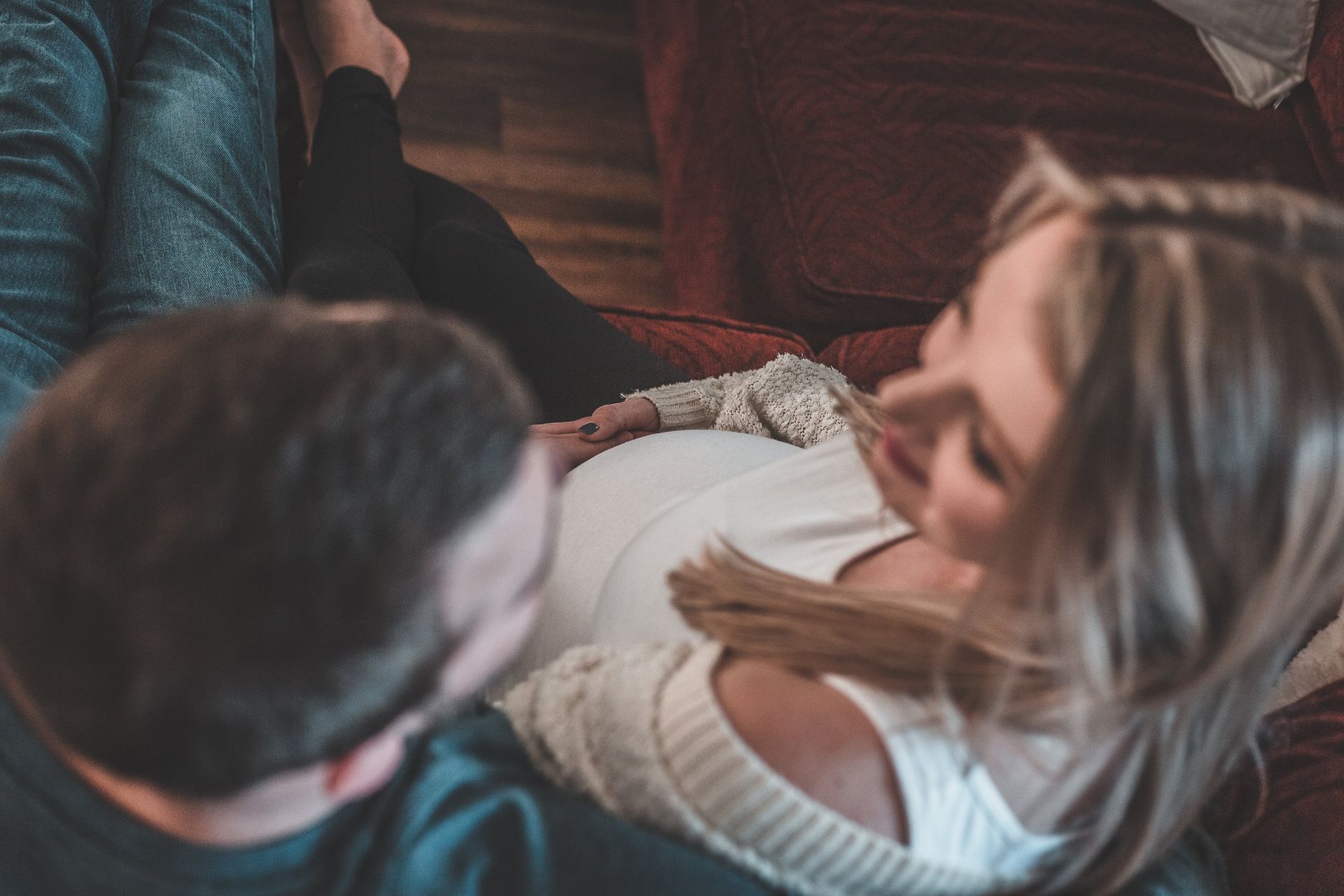 A man and a pregnant woman are sitting on a couch.
