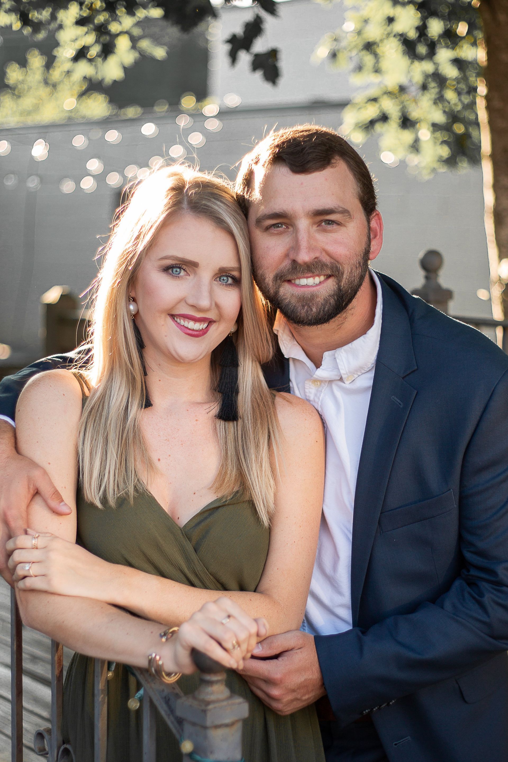 A man in a suit and a woman in a green dress are posing for a picture.