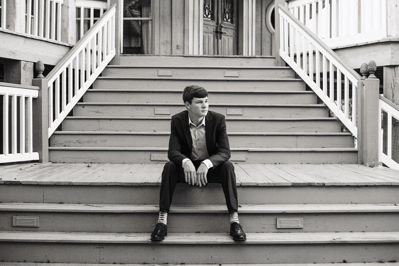 A man in a suit is sitting on the steps of a building.