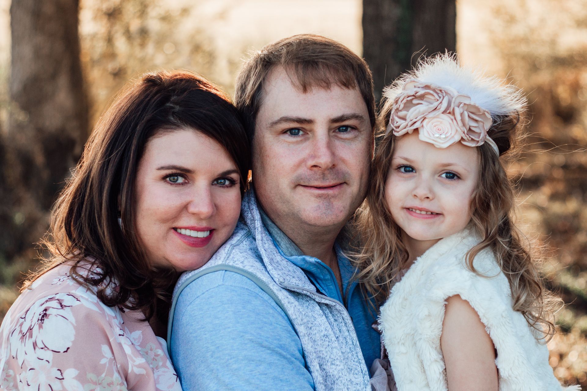 A mother and father pose with their young daughter.