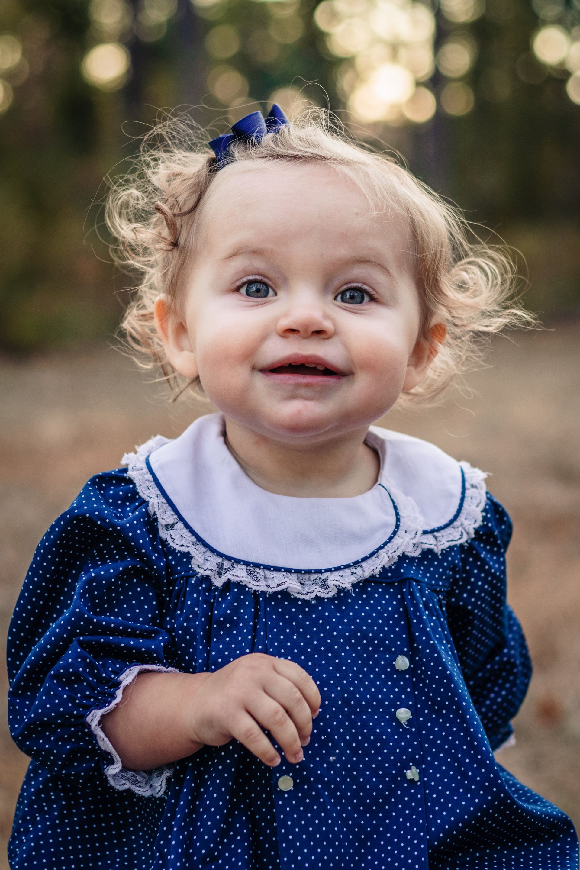A little girl in a blue dress is smiling for the camera.