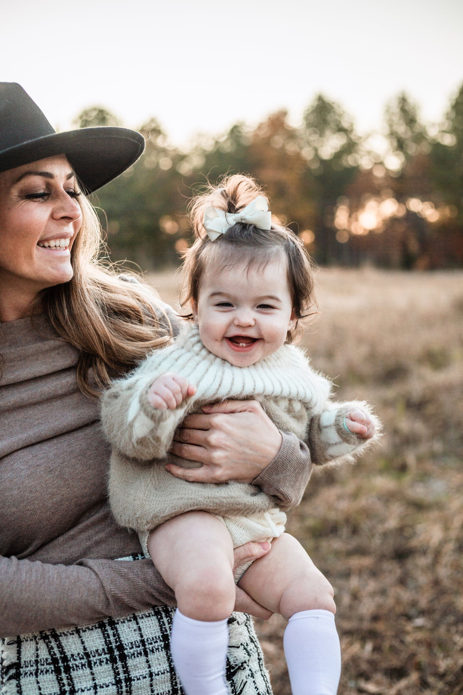 A woman is holding a baby in her arms in a field.