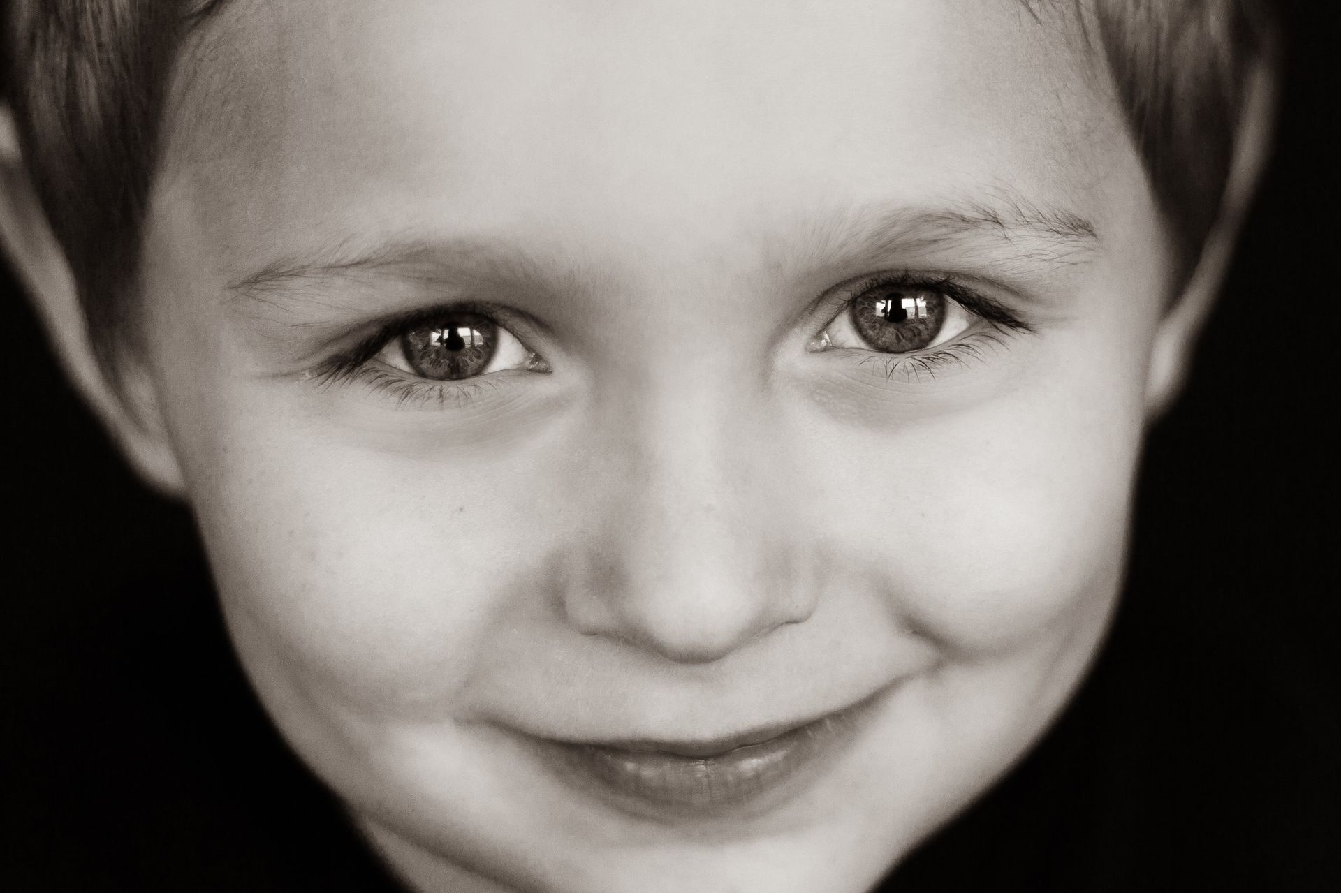A black and white photo of a young boy smiling.