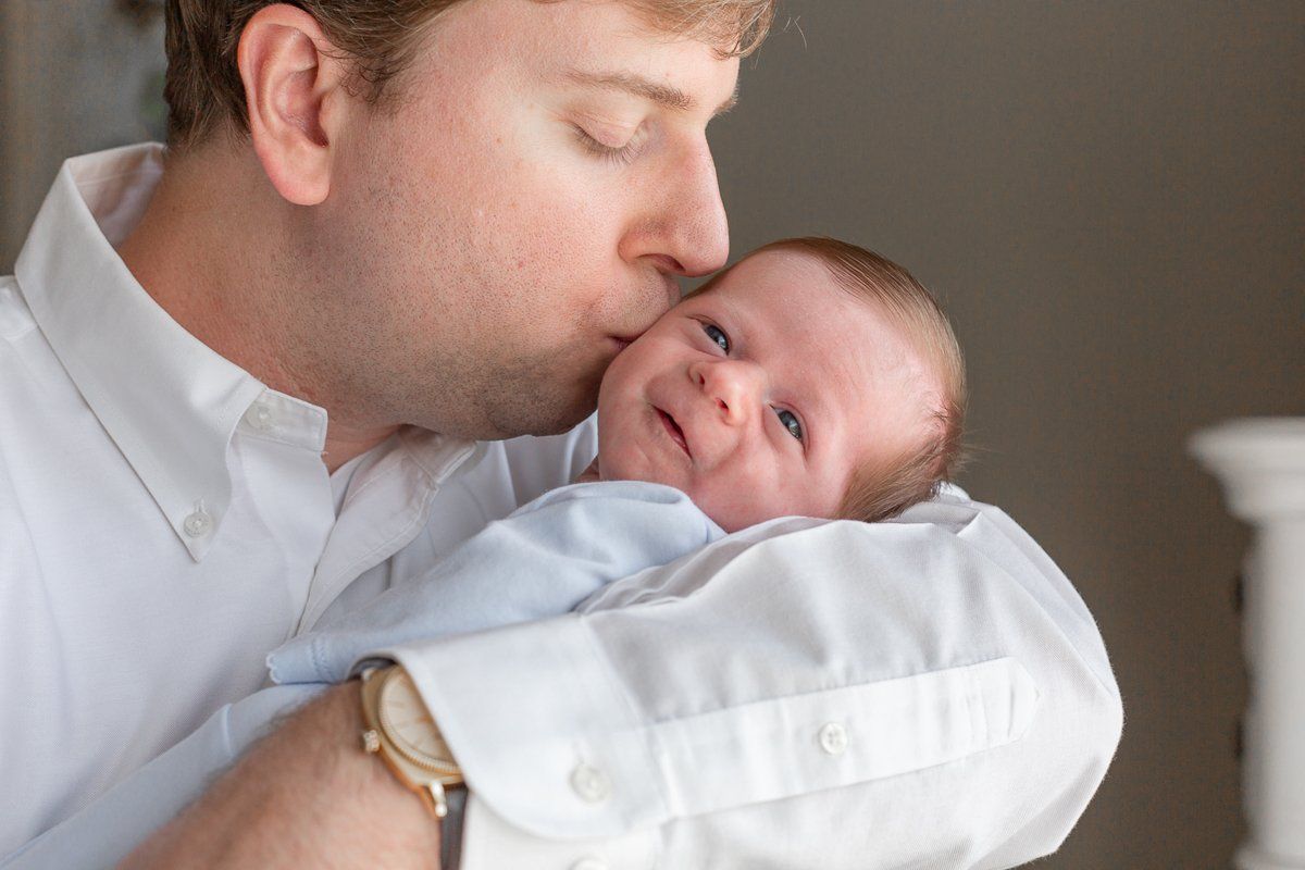 A man is kissing a baby on the cheek.