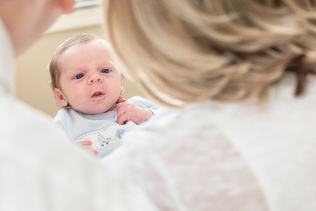 A woman is holding a baby and looking at it in a mirror.