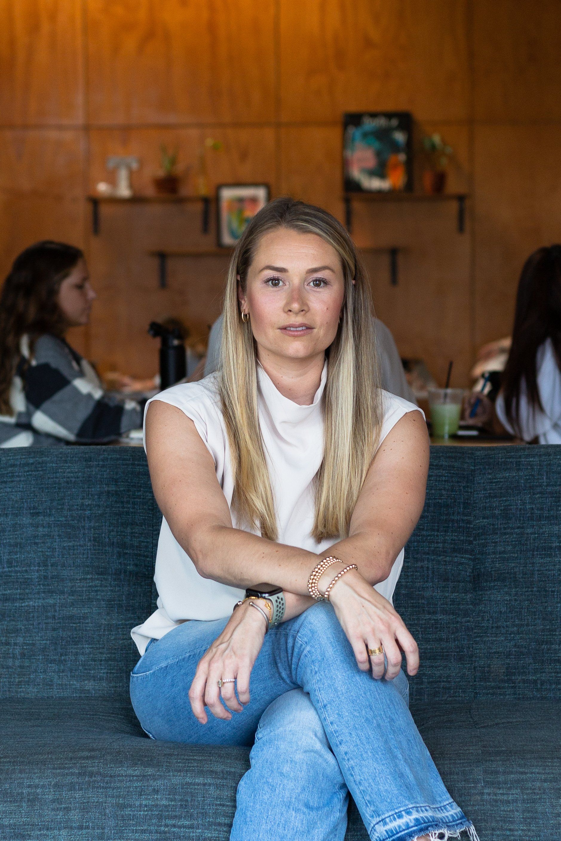 A woman is sitting on a couch in a restaurant with her legs crossed.