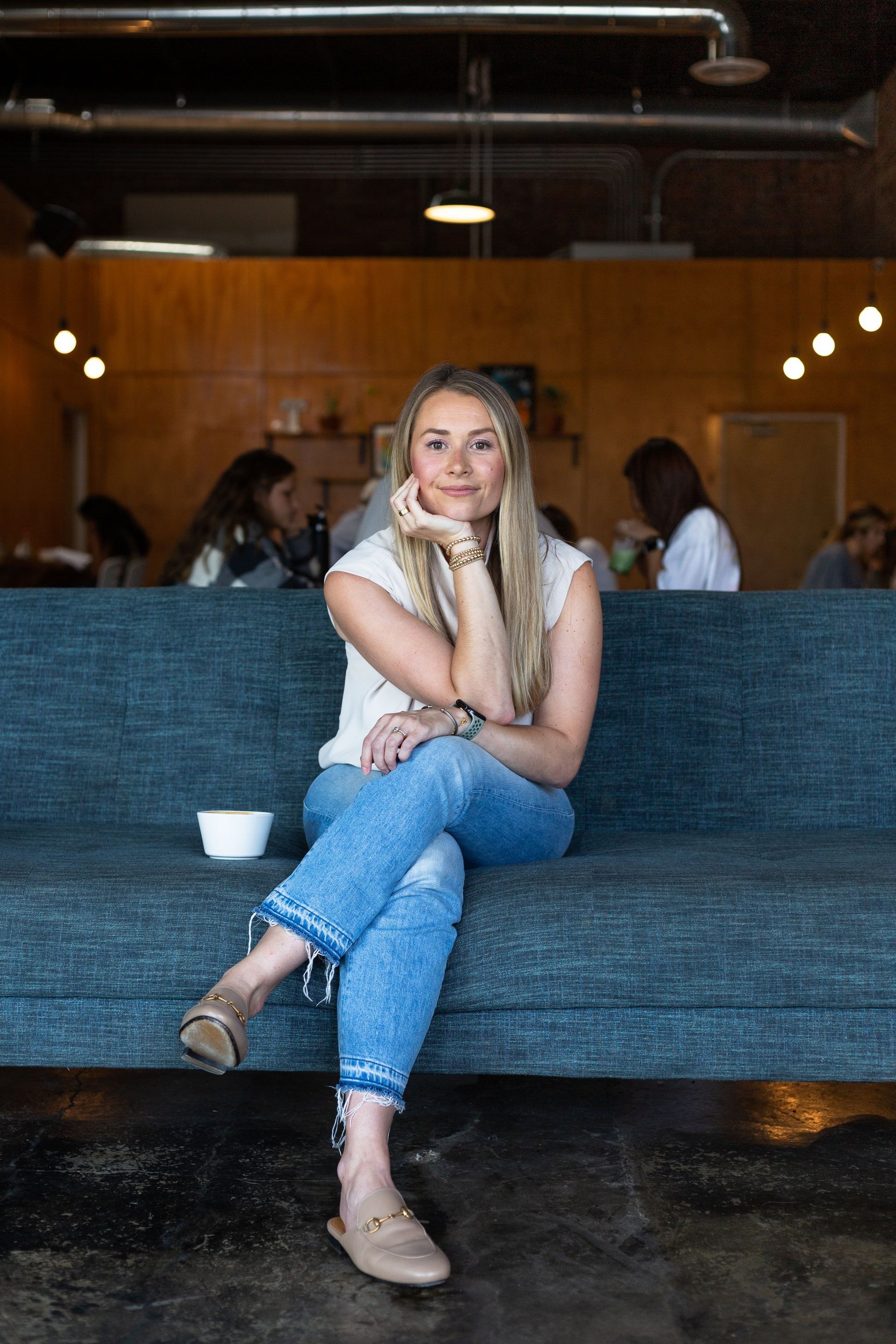 A woman is sitting on a blue couch in a restaurant.