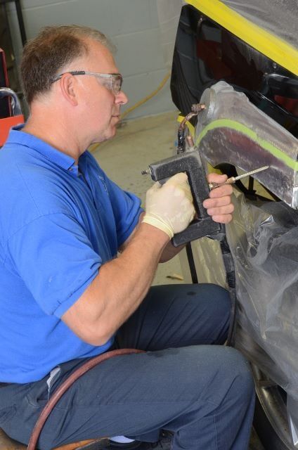 Man Wearing Blue Shirt Using a Power Tool to Repair a Car — Auto Repair in Braintree,, MA