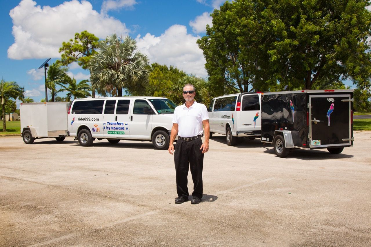 A man is standing in front of a row of vans and trailers.